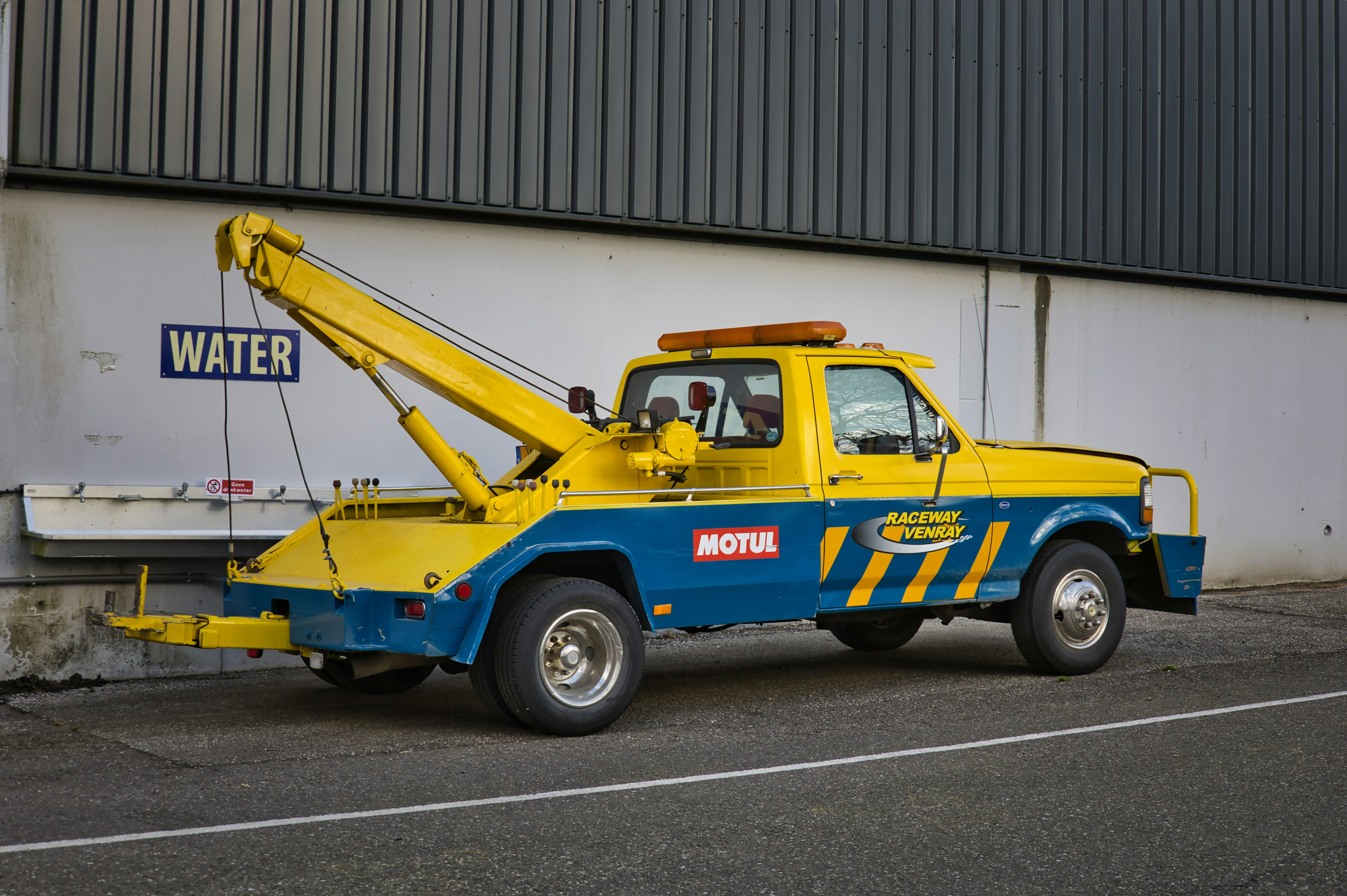 A yellow and blue tow truck parked on the street.