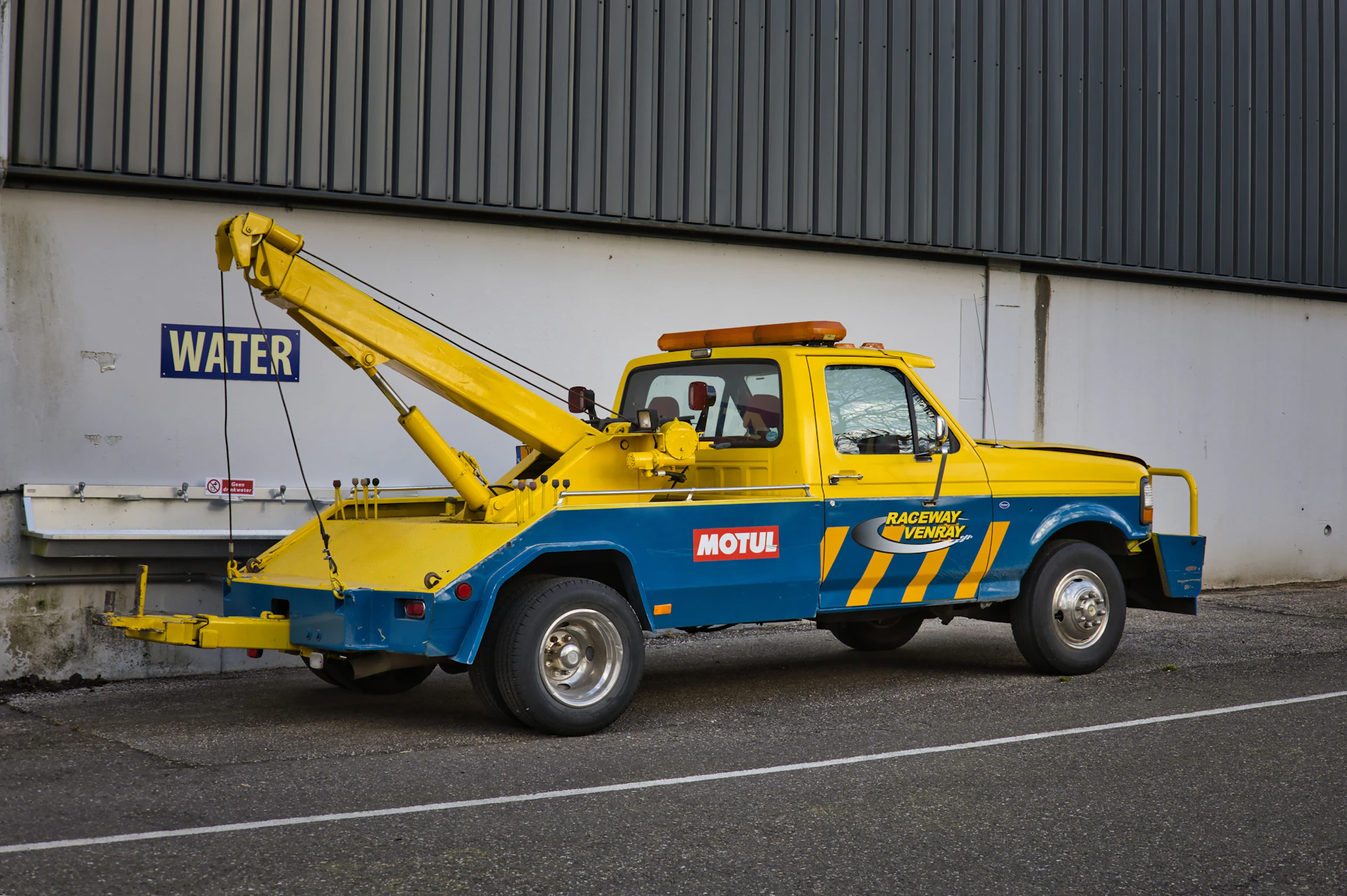A yellow and blue tow truck sits on the street.