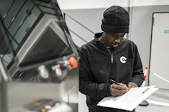 A man is writing by a car.