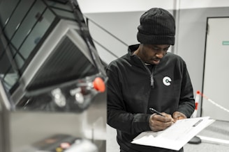 A man is writing by a car.