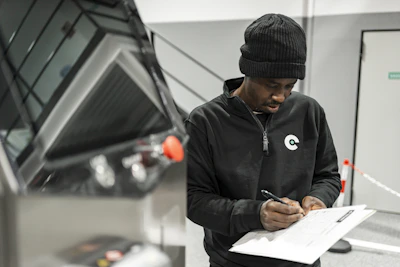 A man is writing by a car.