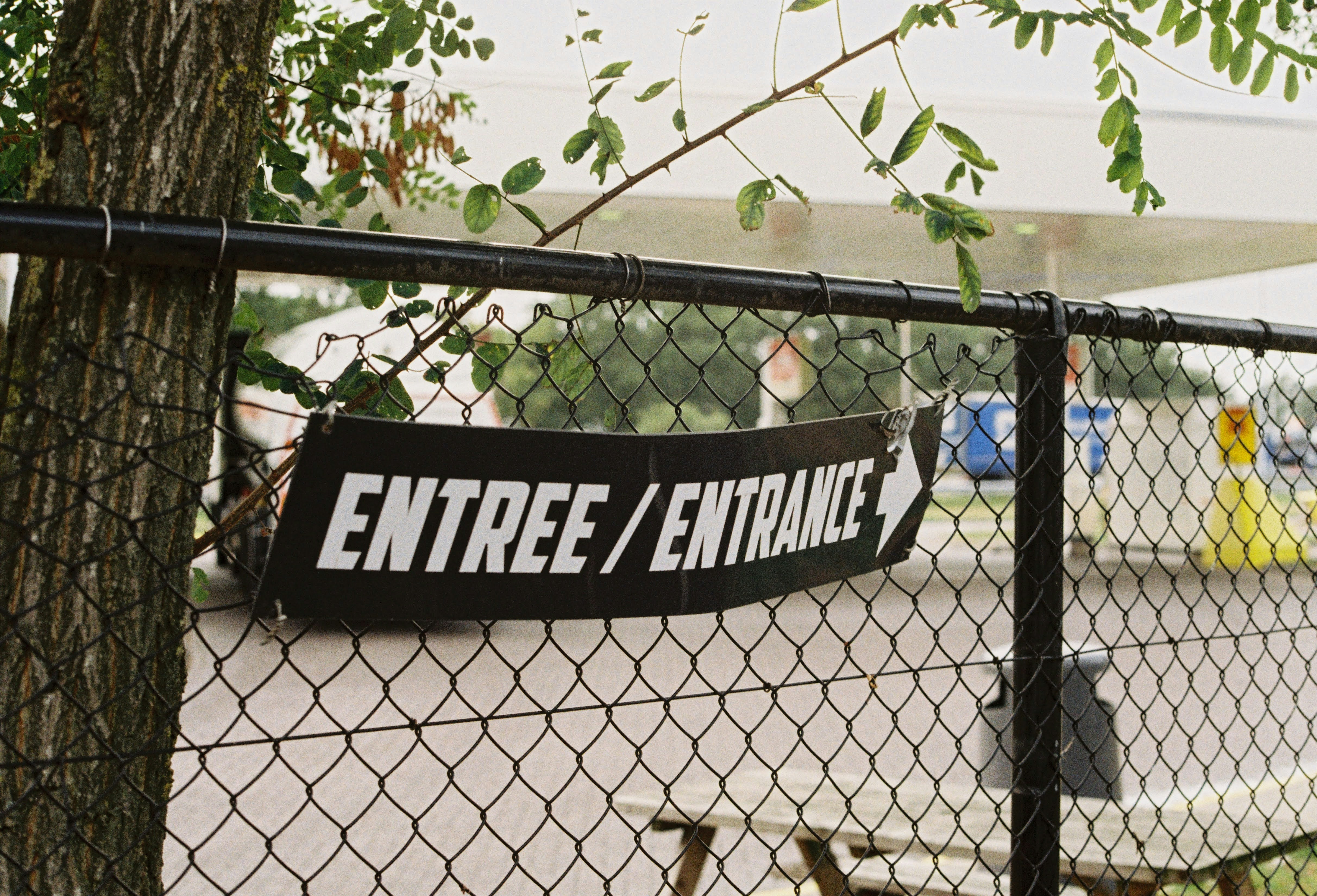 Entrance sign is visible on a black chain link fence.