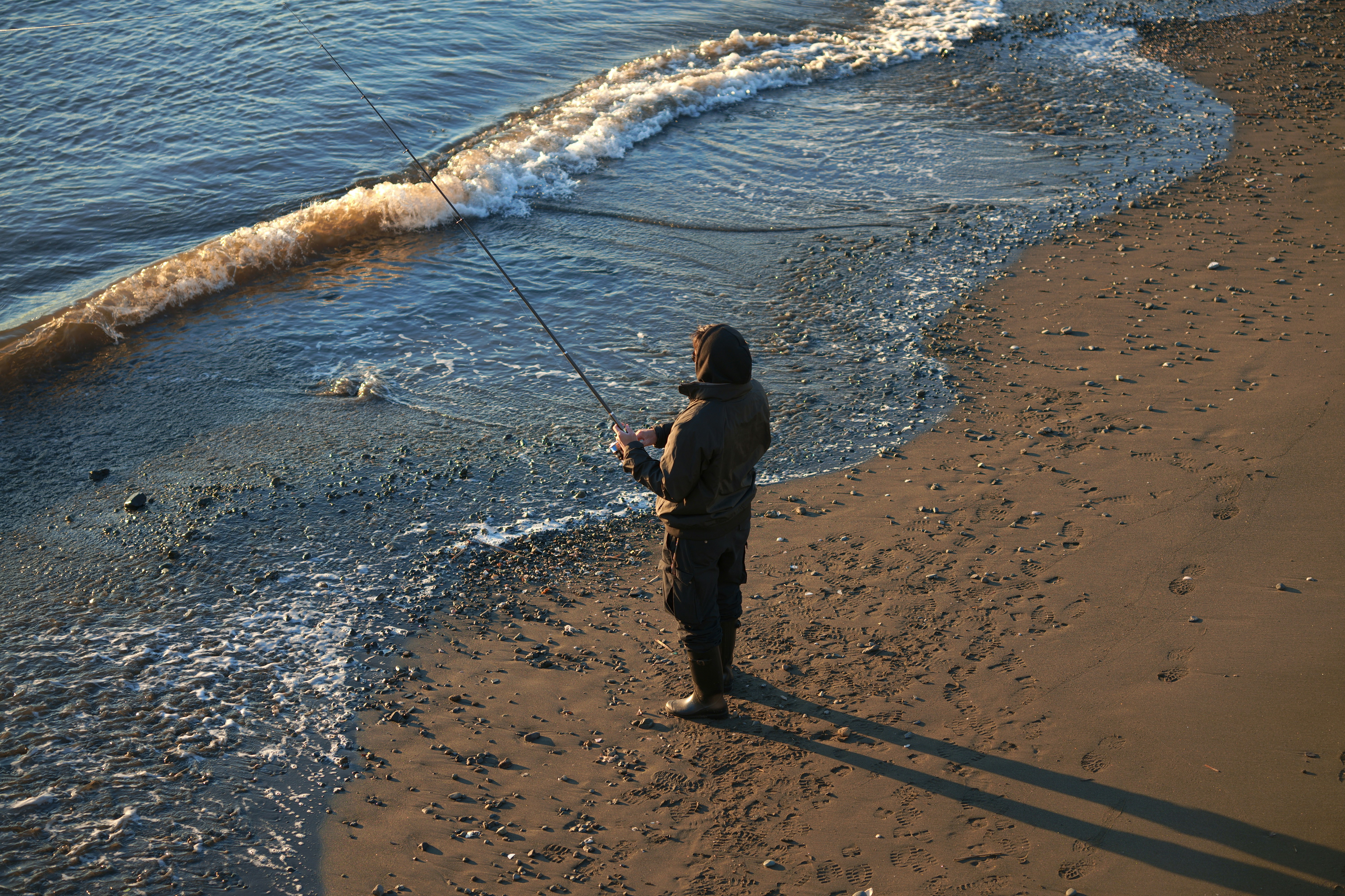 Una persona pesca en la orilla de la playa.