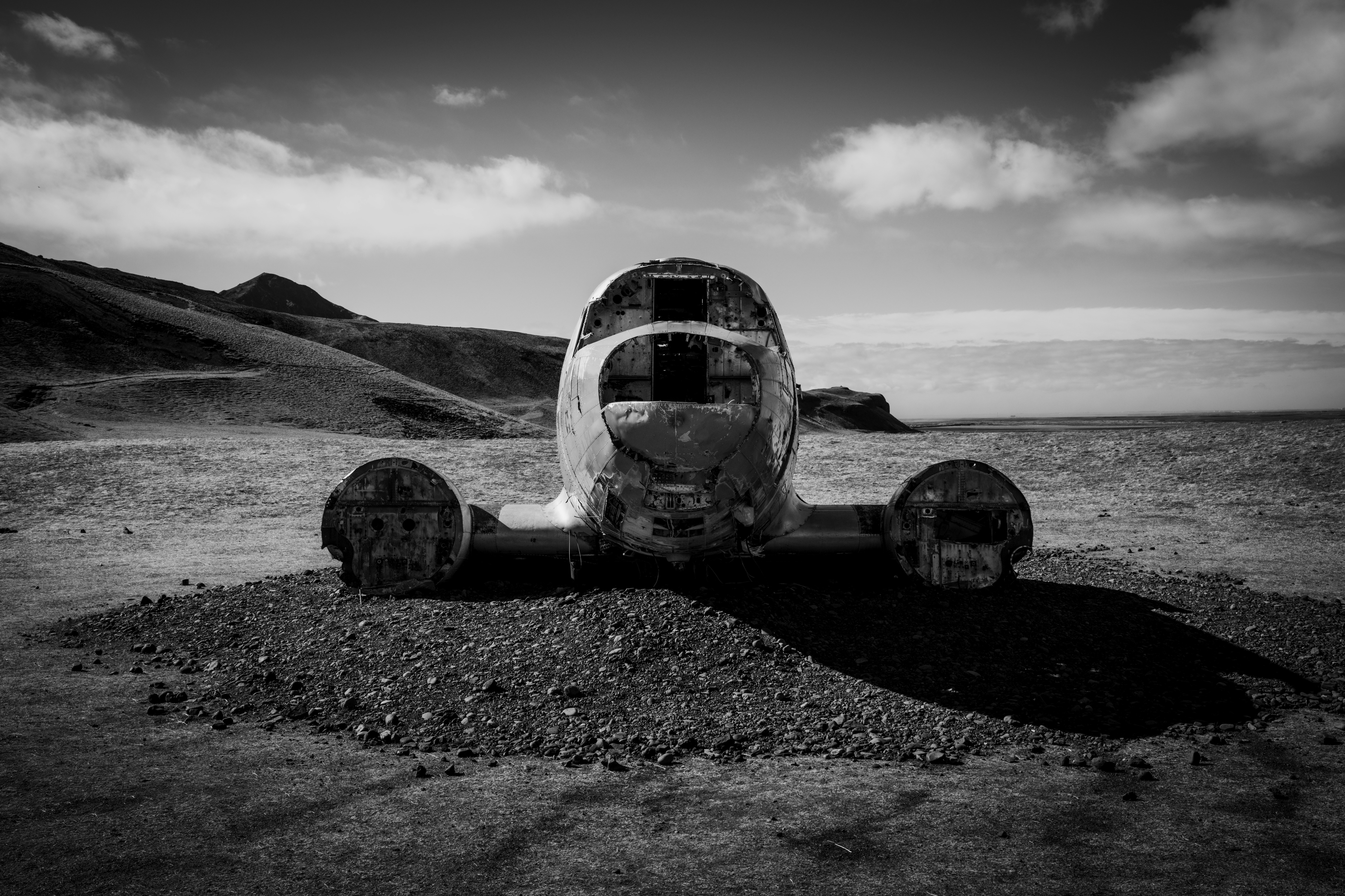 A wrecked plane sits on a barren beach.