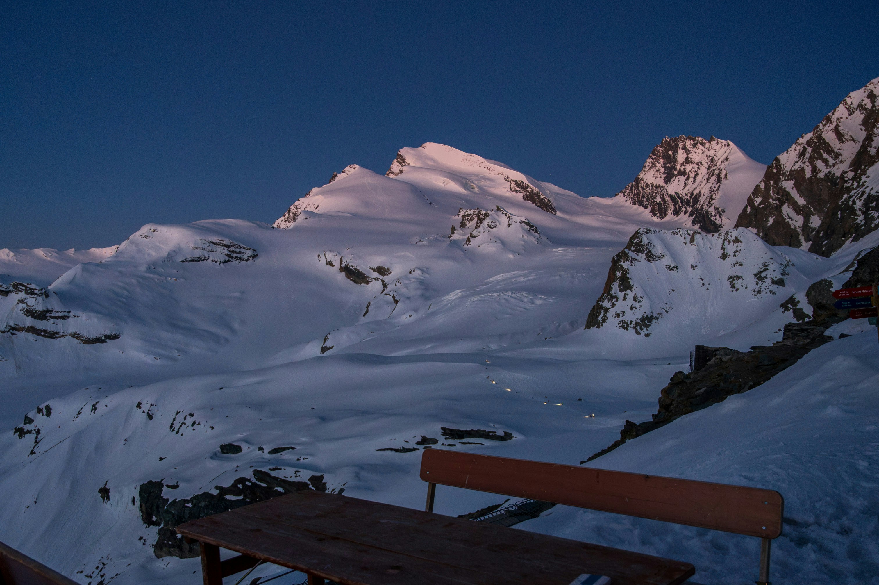 Snow-covered mountains are lit by the sun.