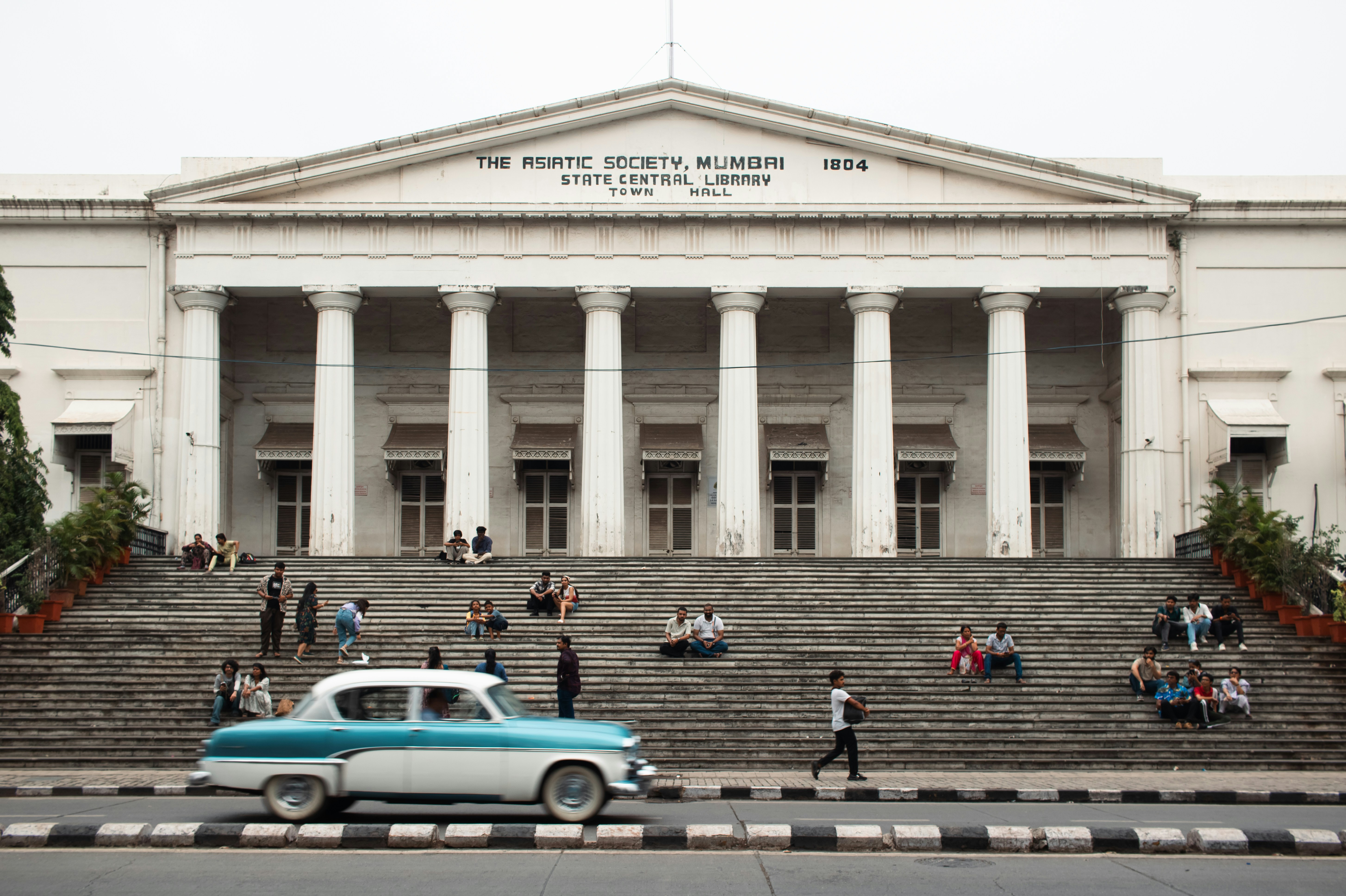A classic building with people and a car.