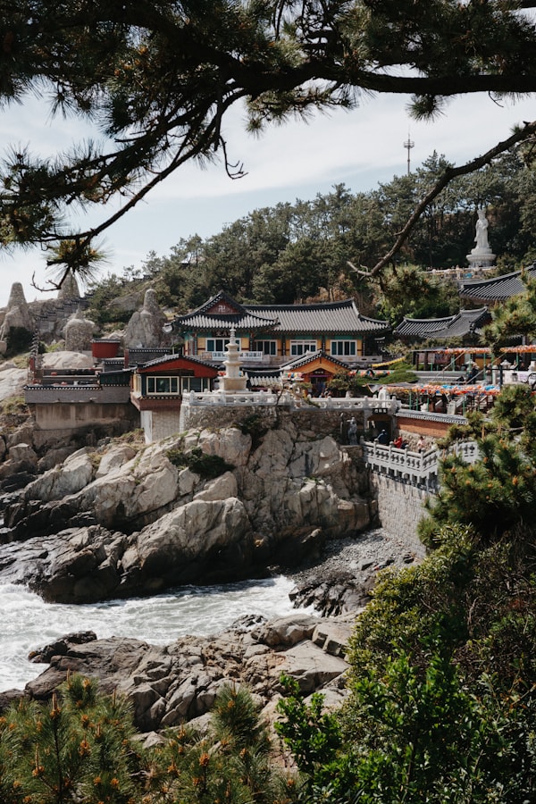 Coastal temple nestled among rocks and trees.