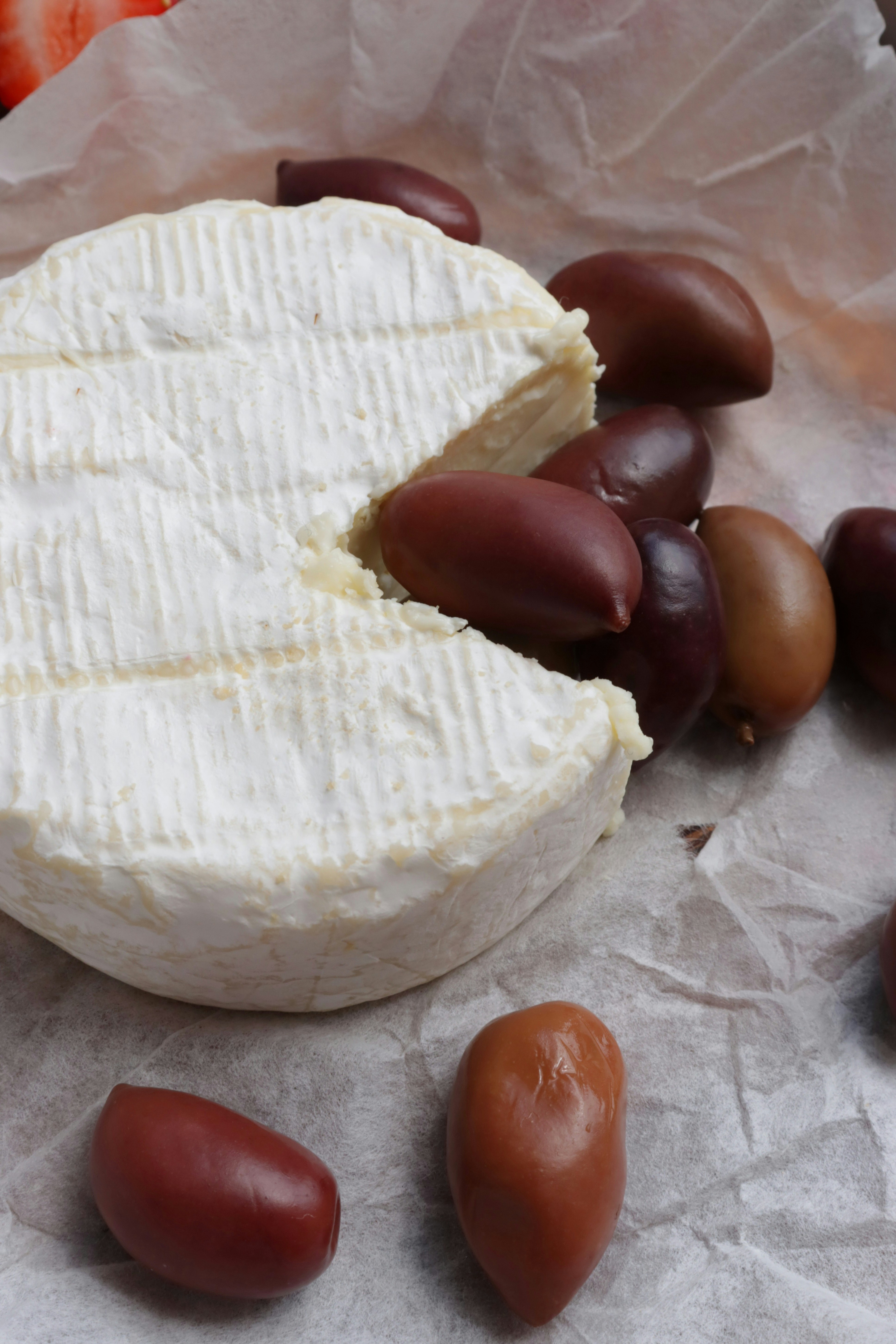 Cheese and olives arranged on parchment paper.