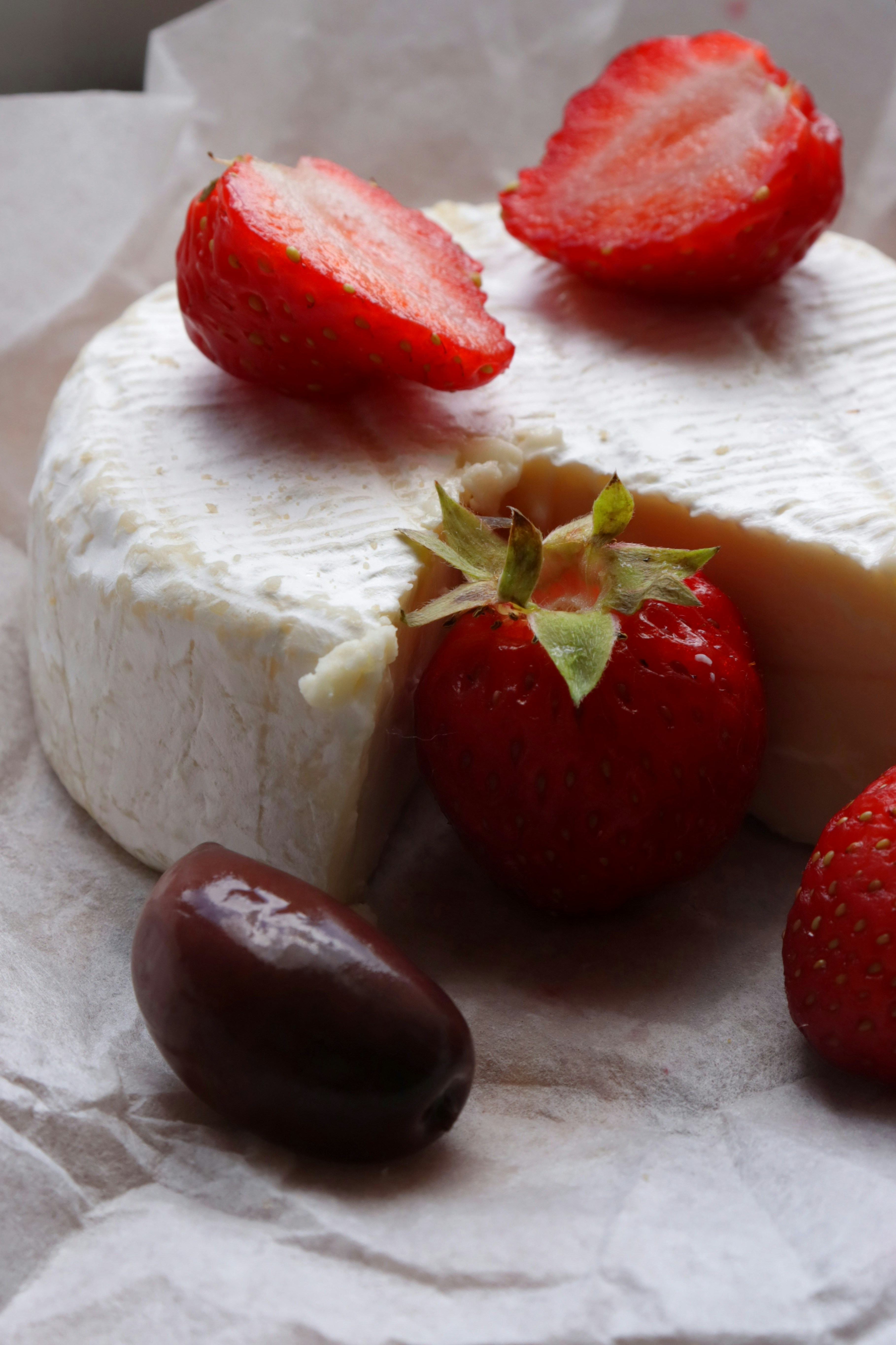 Strawberries and brie cheese displayed on parchment.