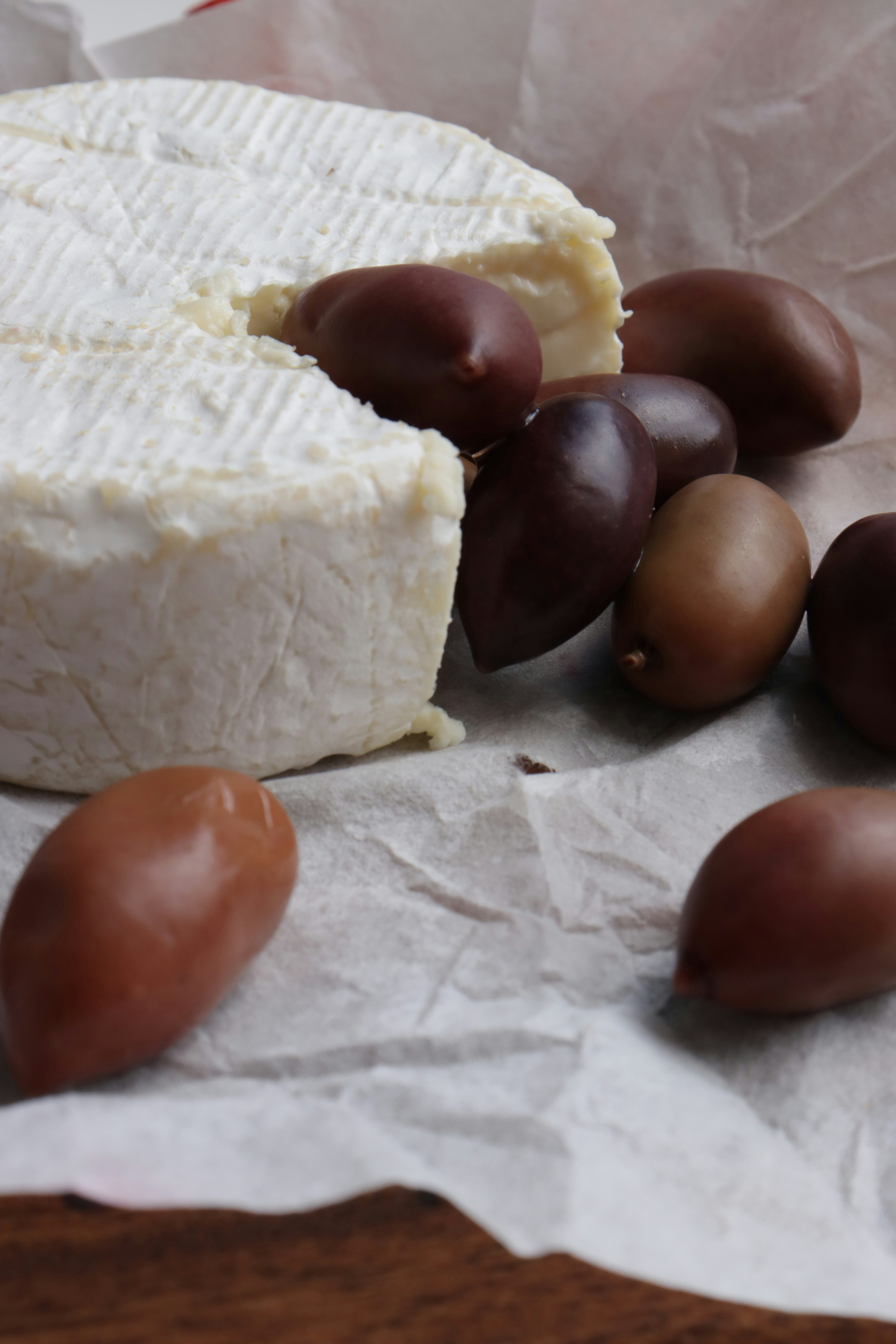 Cheese and olives on a paper-lined surface.