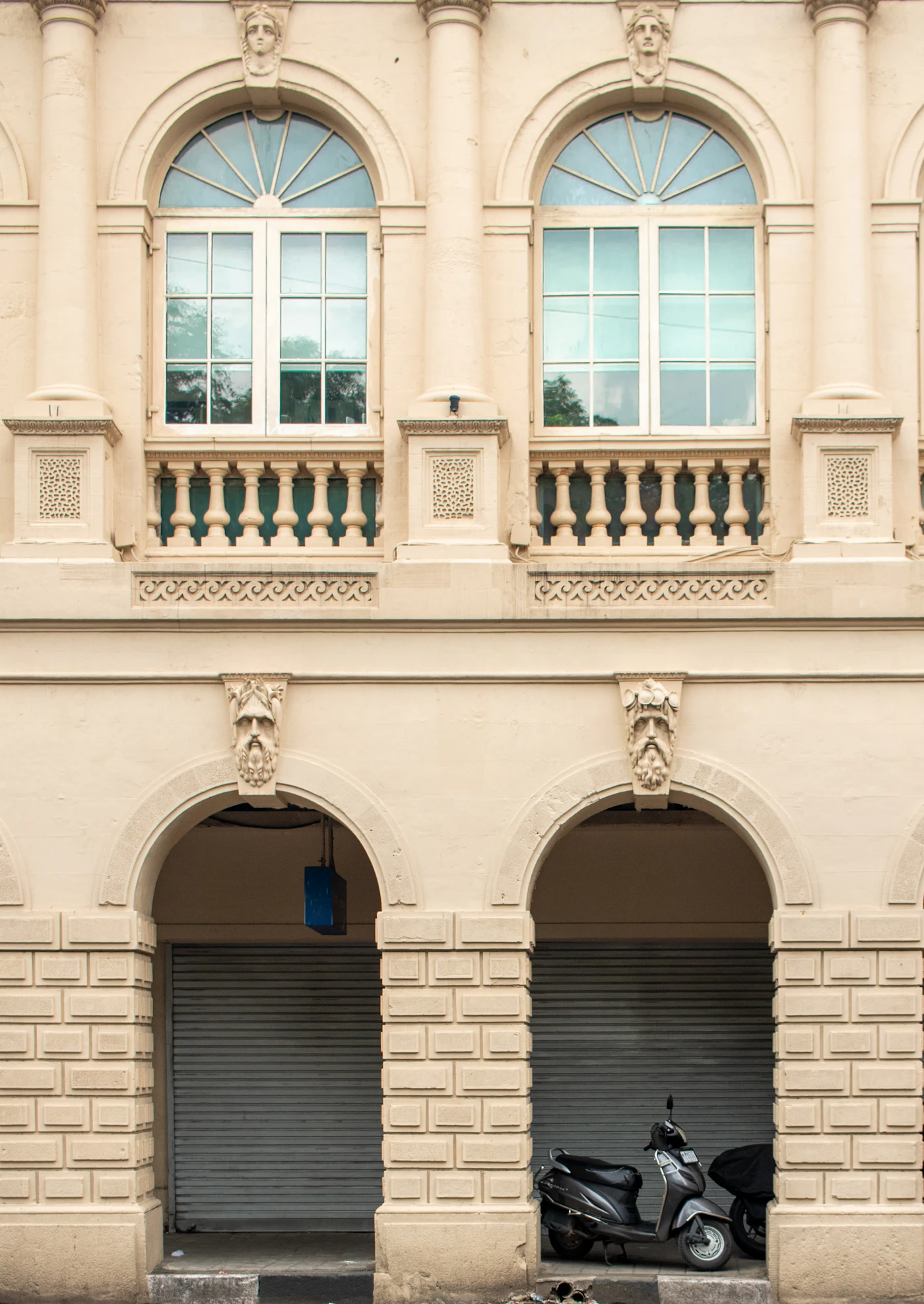 An ornate stone façade with arched windows on a street in Fort, Mumbai