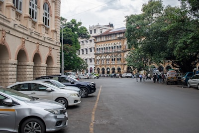 Cars are parked along a road with old buildings.