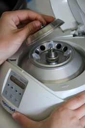 A hand is opening a centrifuge machine.