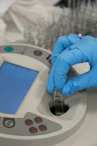 Scientist placing a sample cuvette into laboratory analysis equipment.