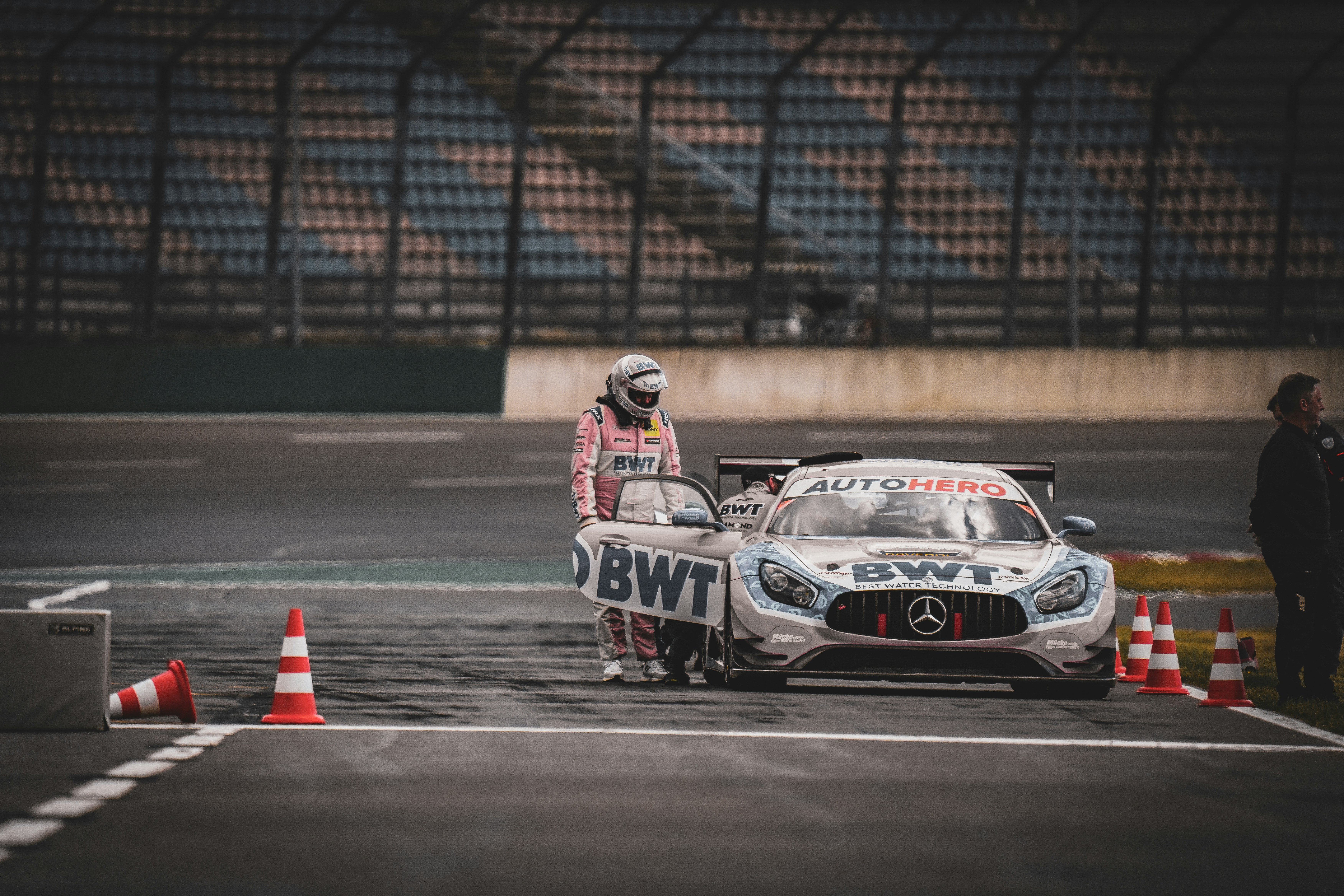 A racer exits their car on the racetrack.
