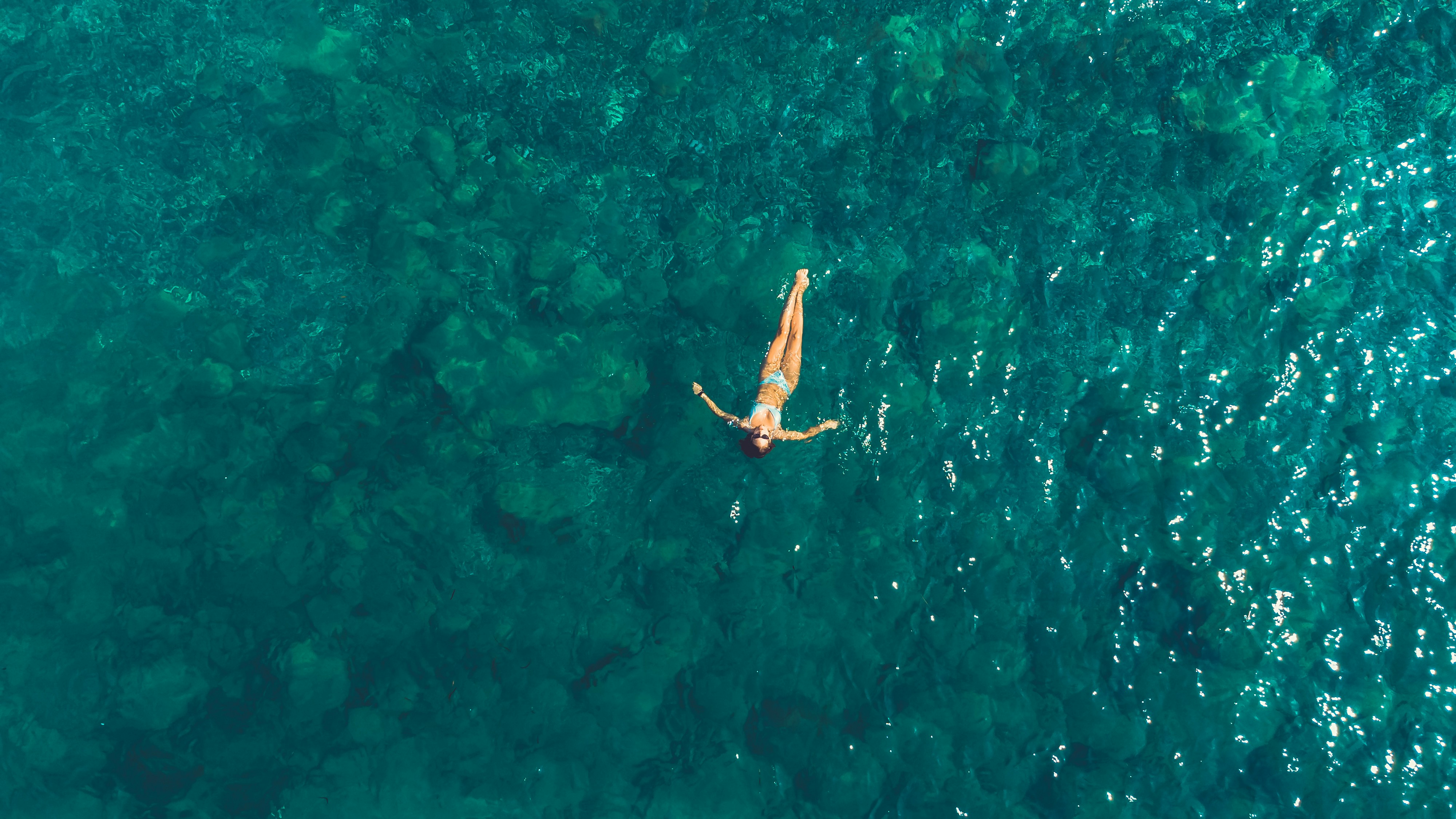 A person swims in crystal clear ocean water.