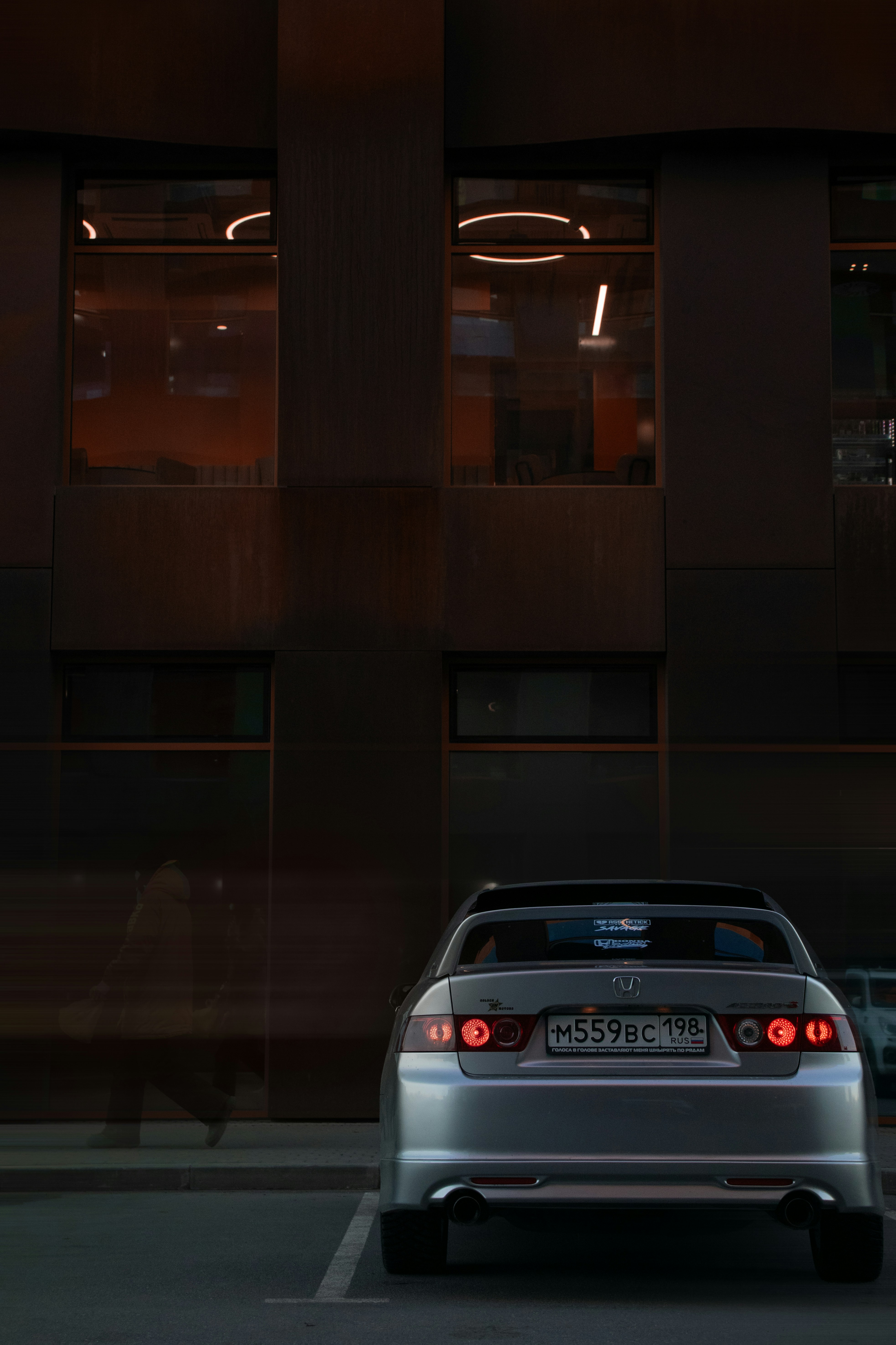 A silver honda accord is parked near a building.