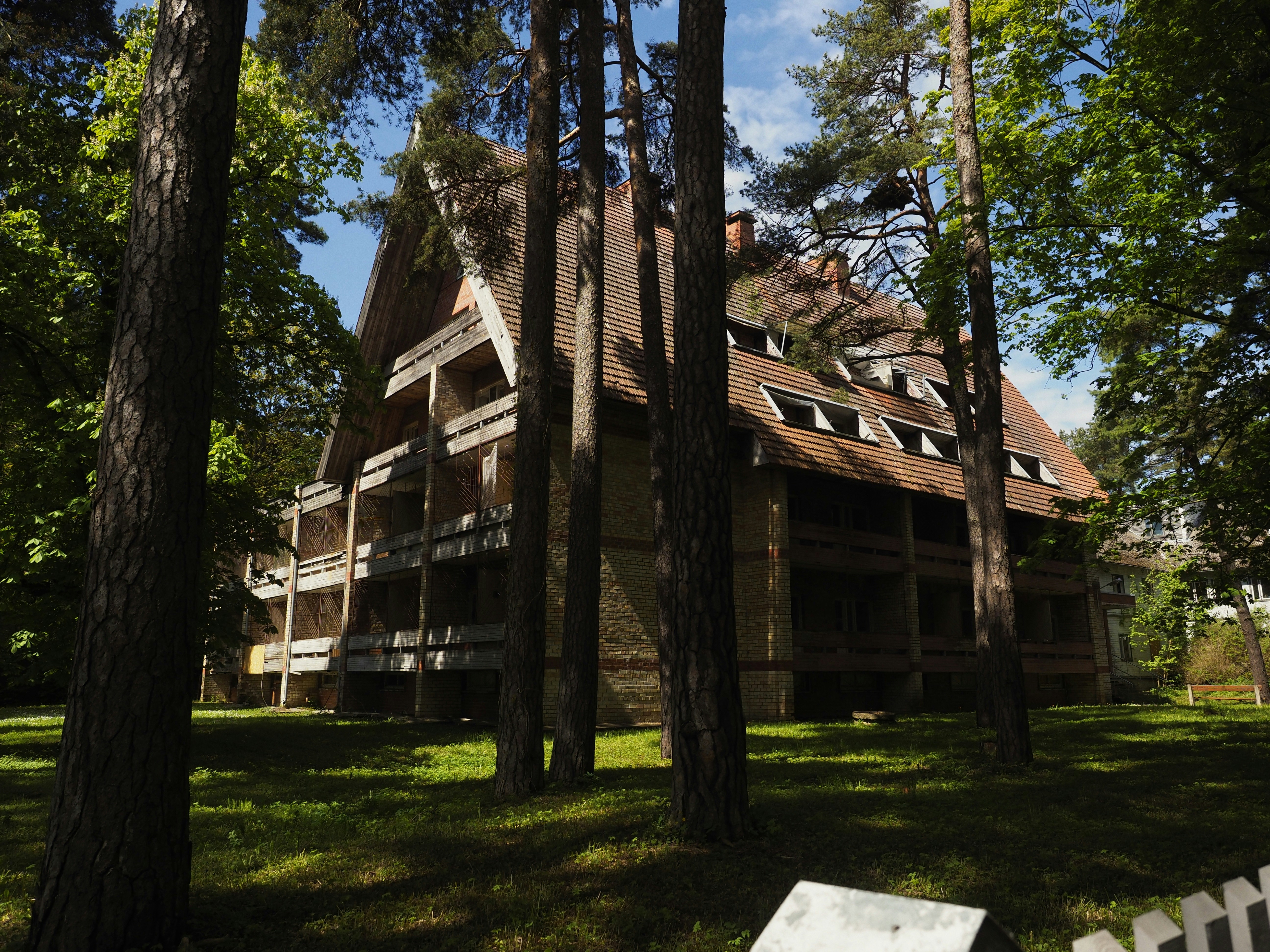 Ein großes Haus ist von hohen Bäumen umgeben.