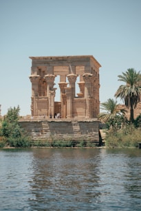 Ancient egyptian temple stands beside the calm water.