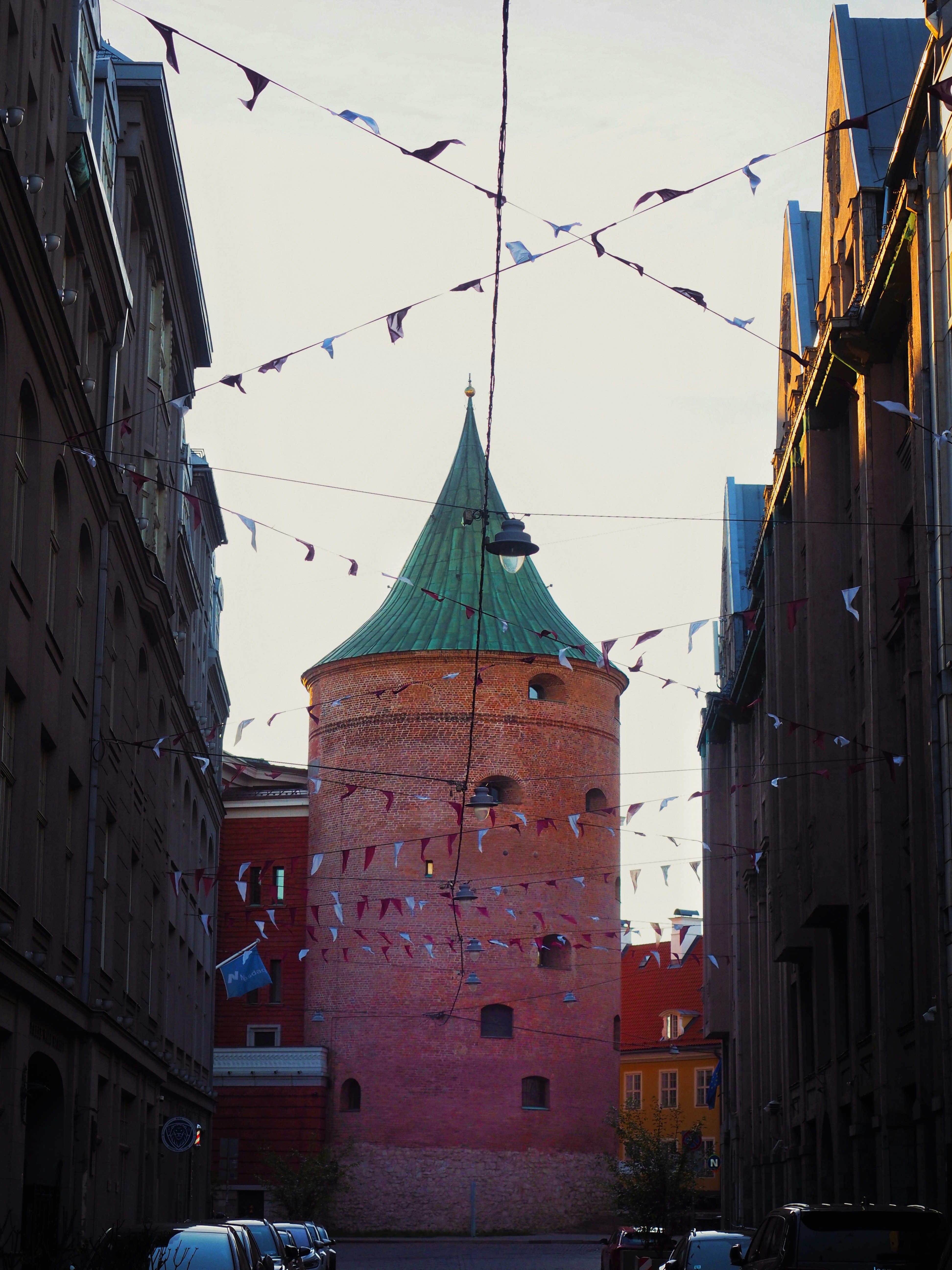 Zwischen Gebäuden steht ein Backsteinturm.