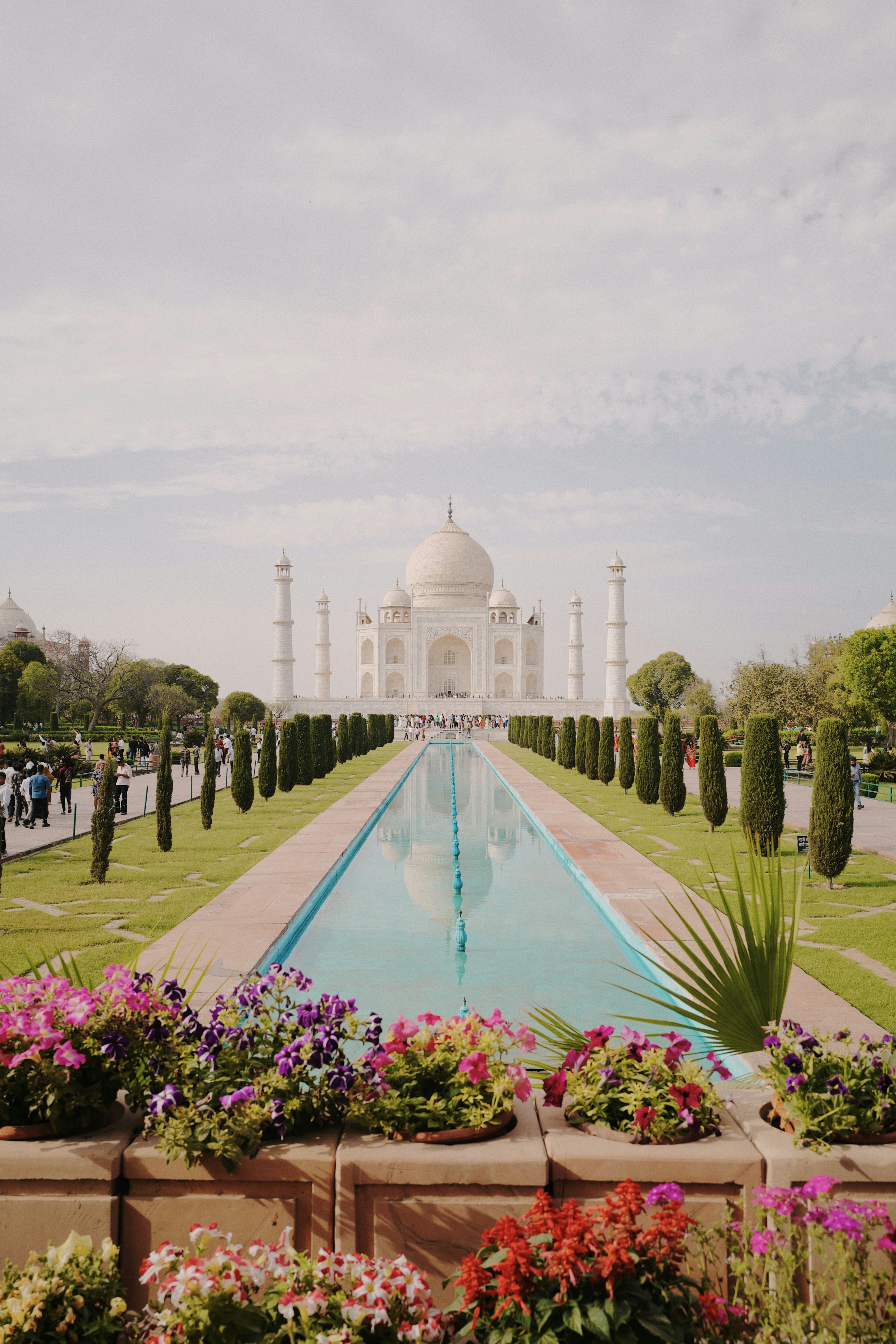The taj mahal is reflected in a long pool.