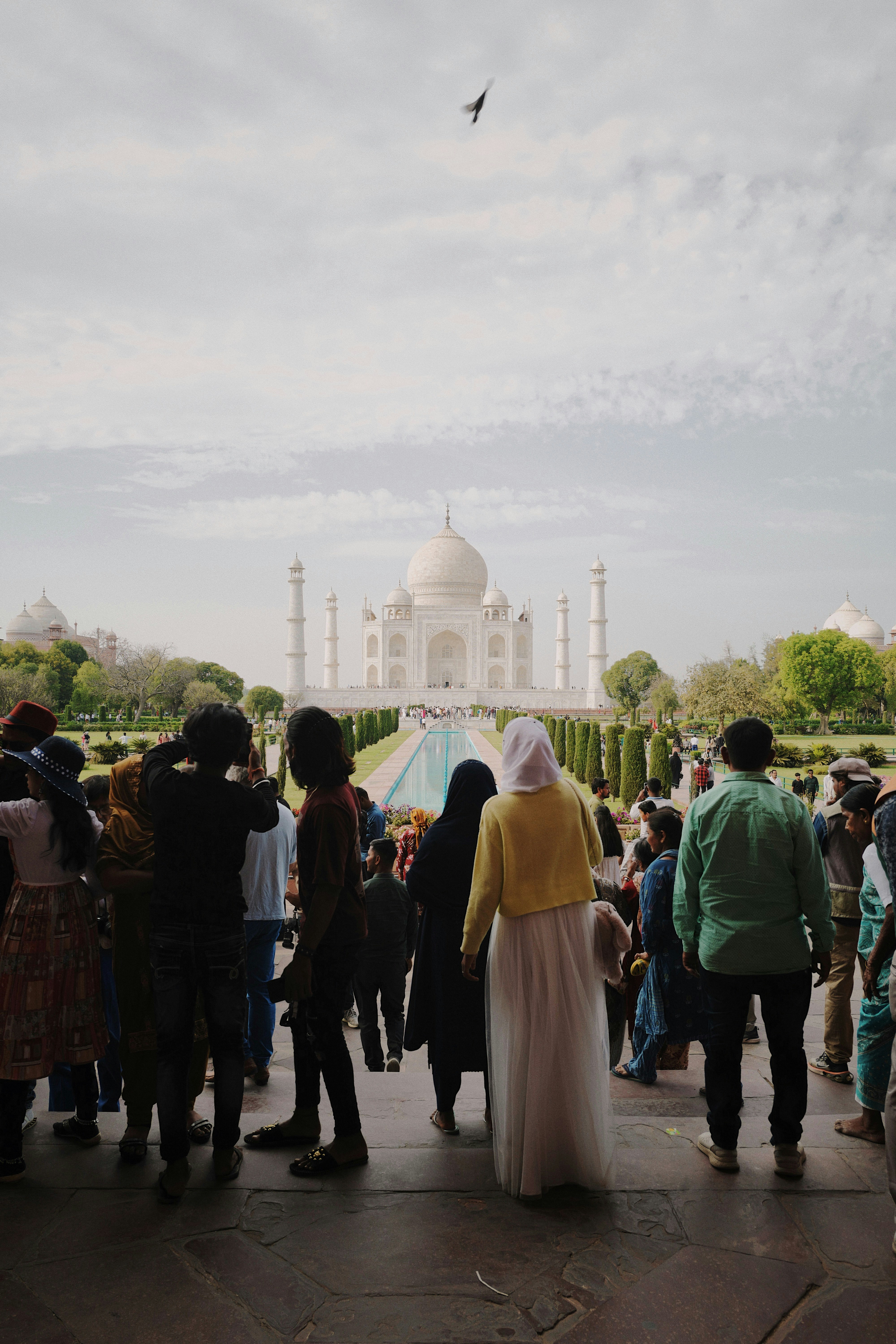 Tourists admire the taj mahal on a bright day.