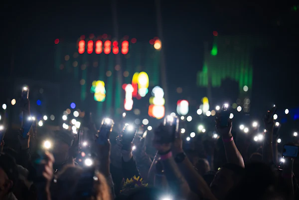 A crowd holding up glowing phones in the dark