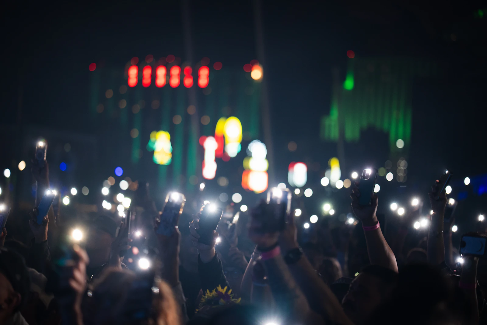 A crowd holding up glowing phones in the dark