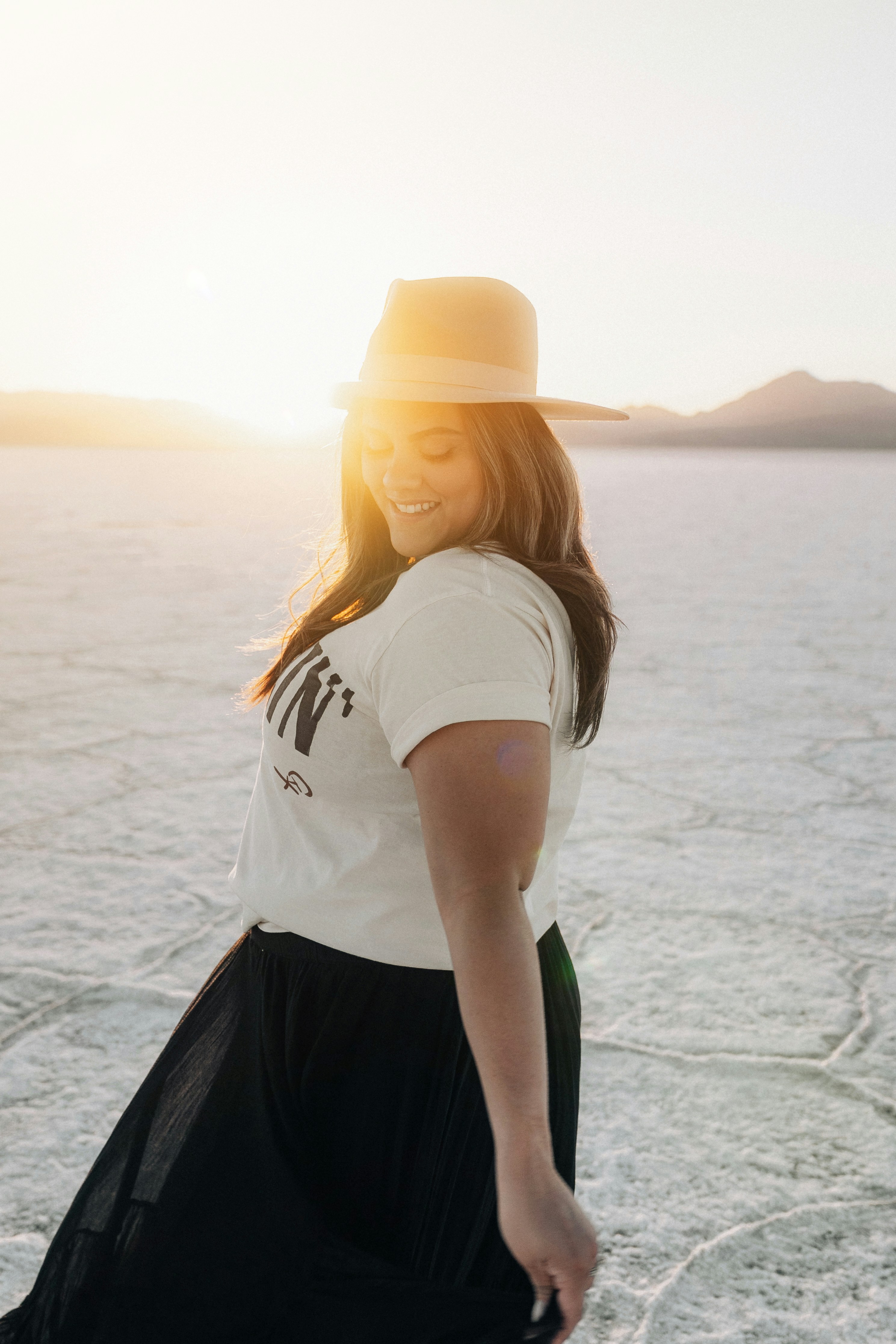 Woman smiles and poses in a field at sunset