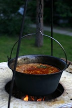 Soup is being cooked in a large hanging pot.