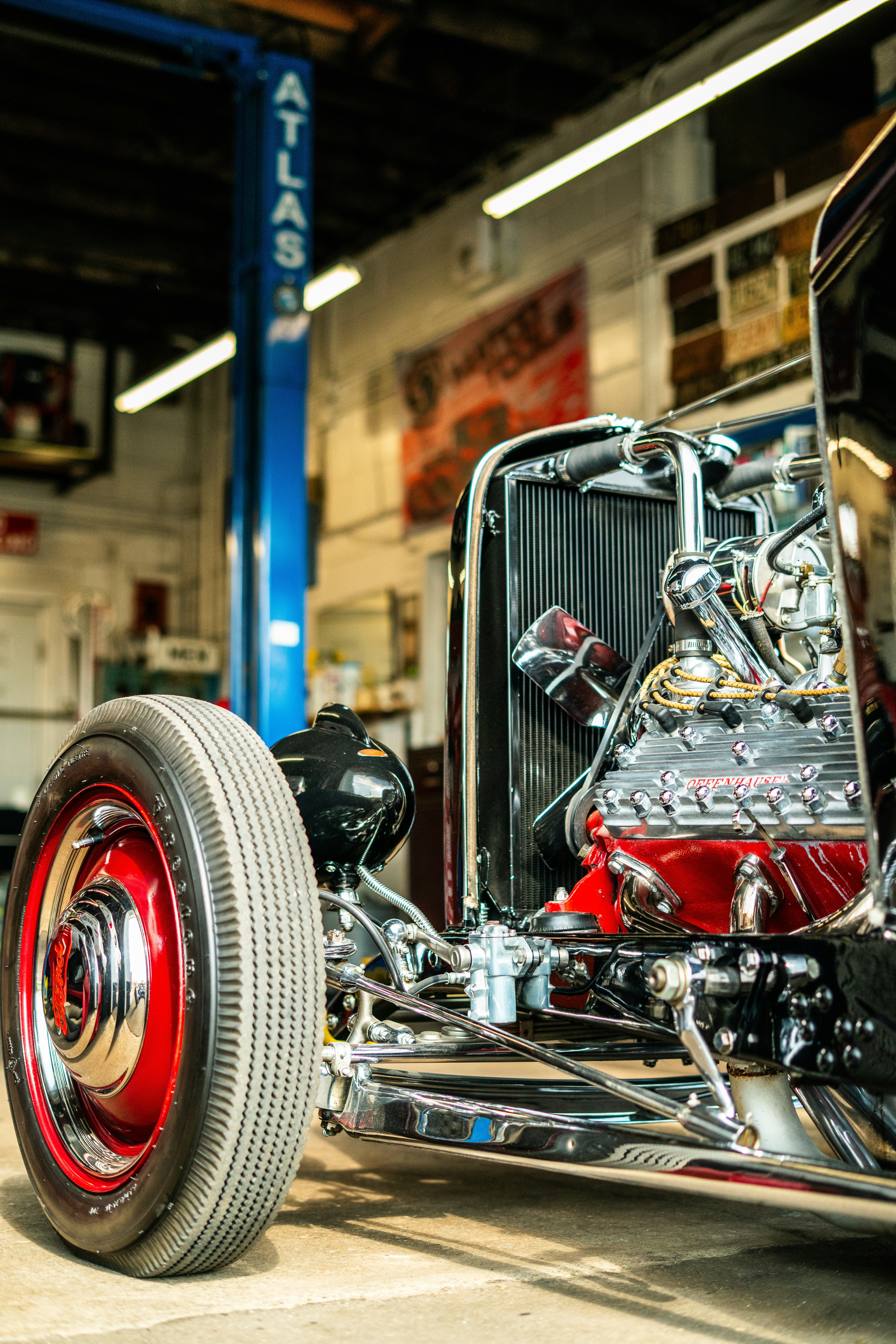 A vintage hot rod car sits in a garage.