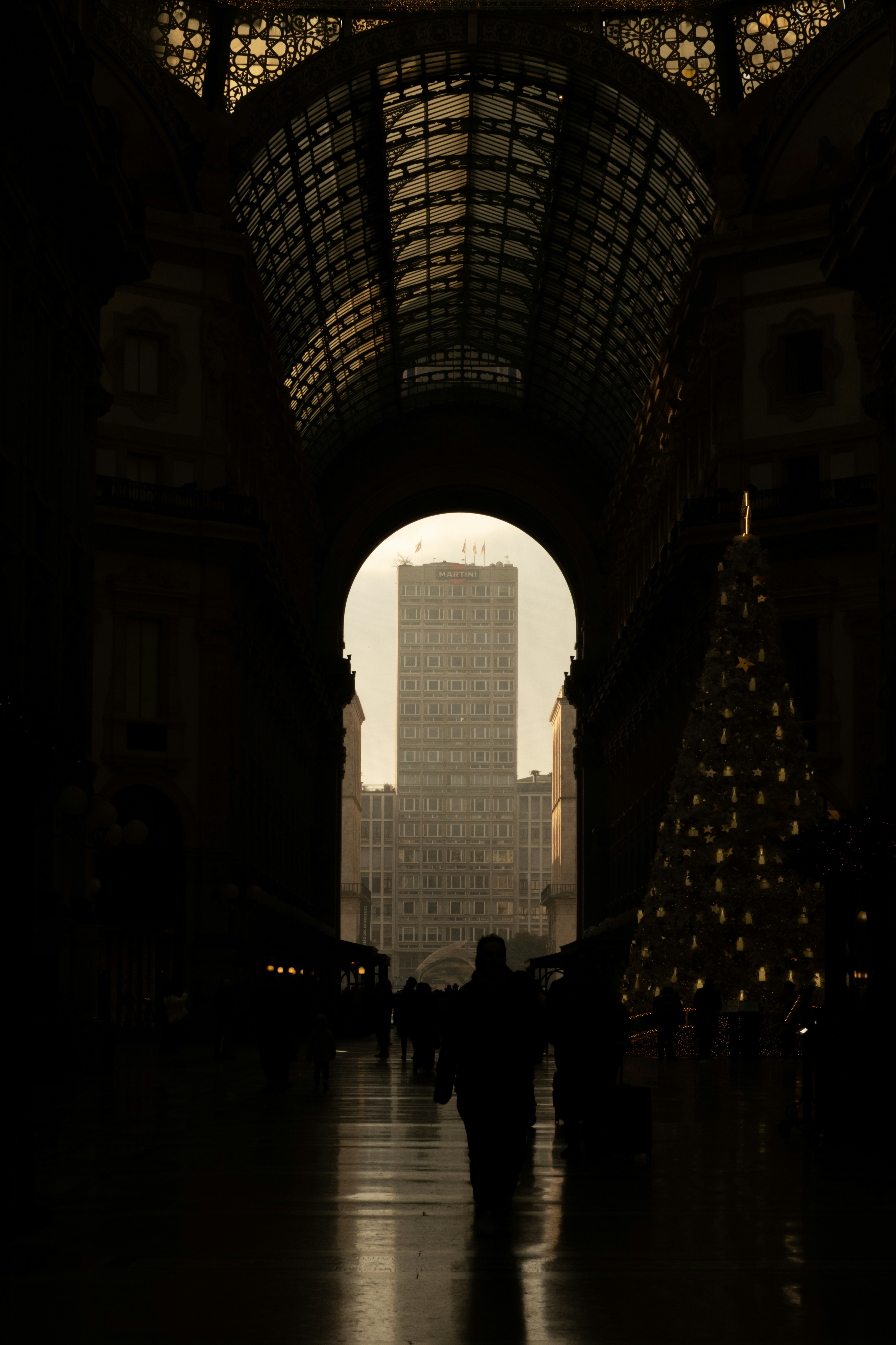 A silhouette views a building through an archway