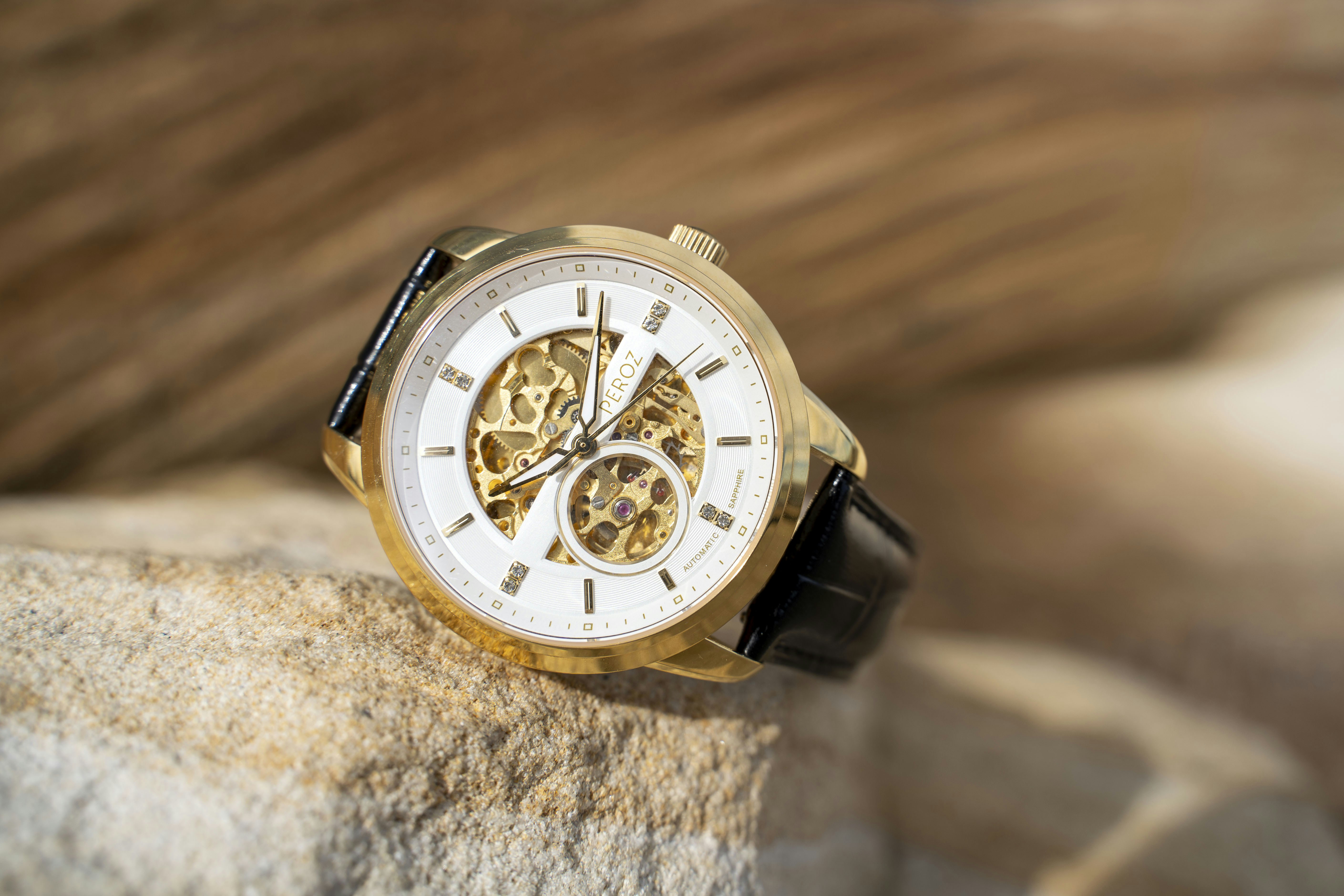 Un orologio scheletrato d'oro poggia su una pietra.