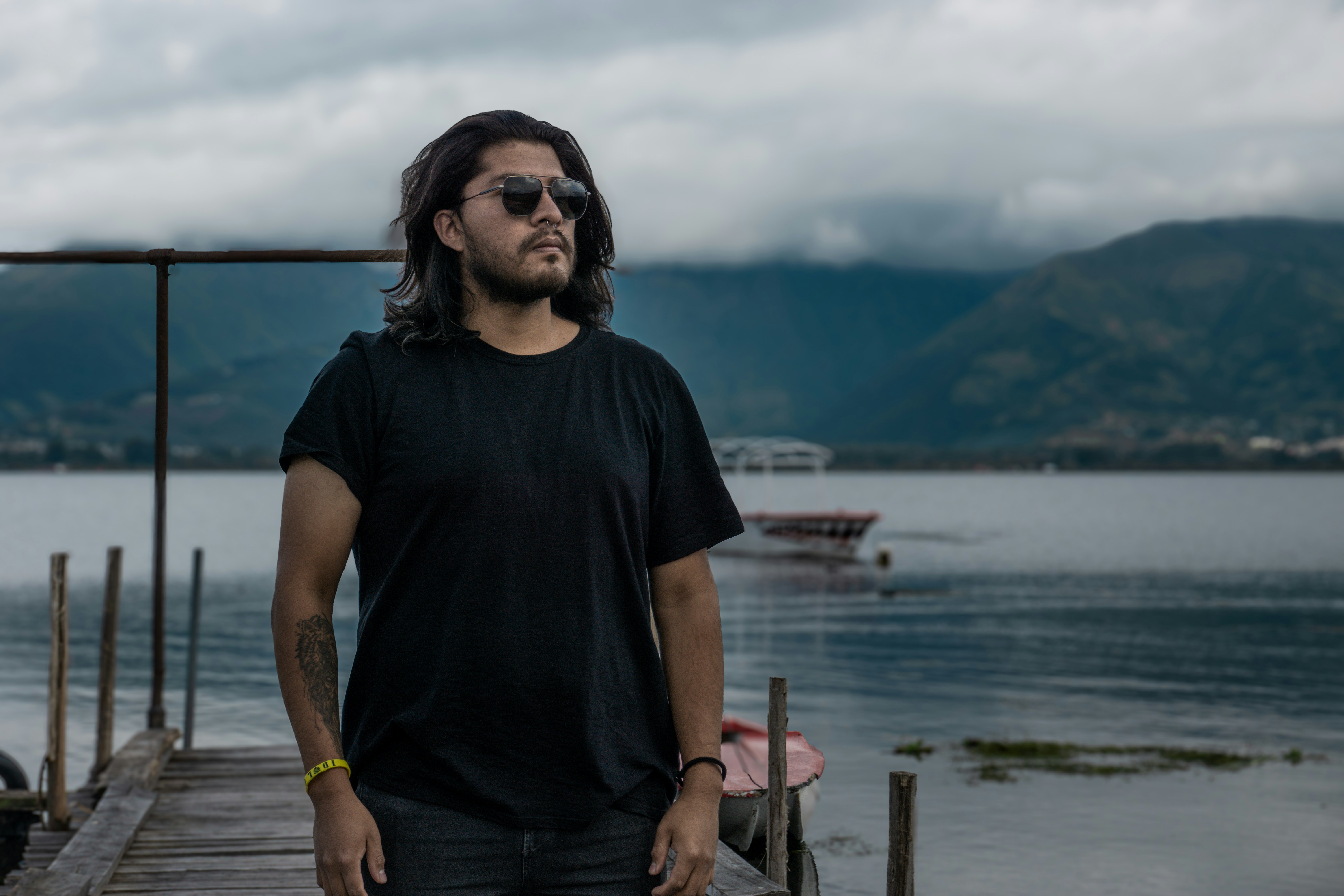 Man with sunglasses stands on a wooden pier.