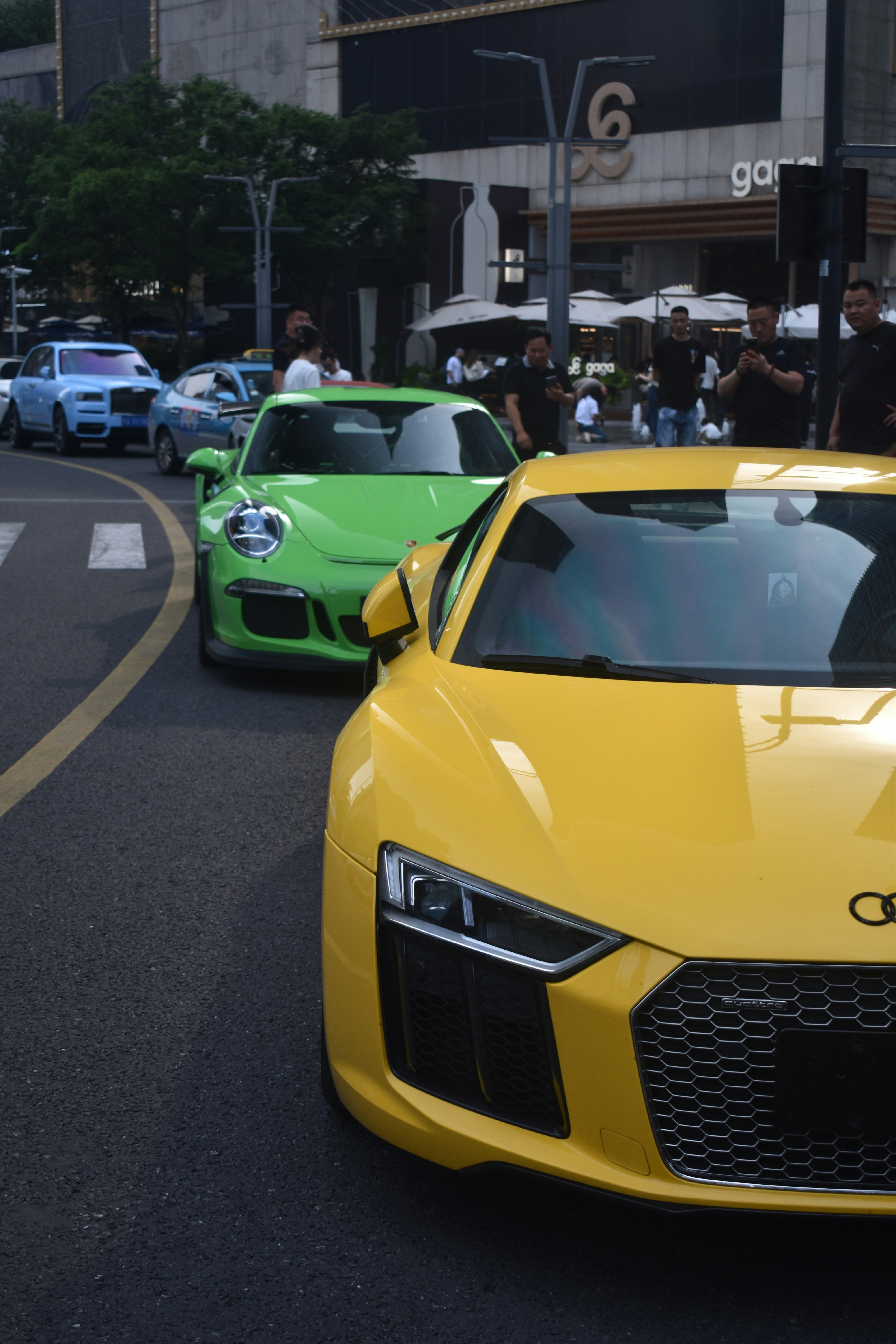 Luxury cars line up on the city street.