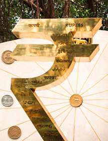 A golden rupee symbol with indian currency details.