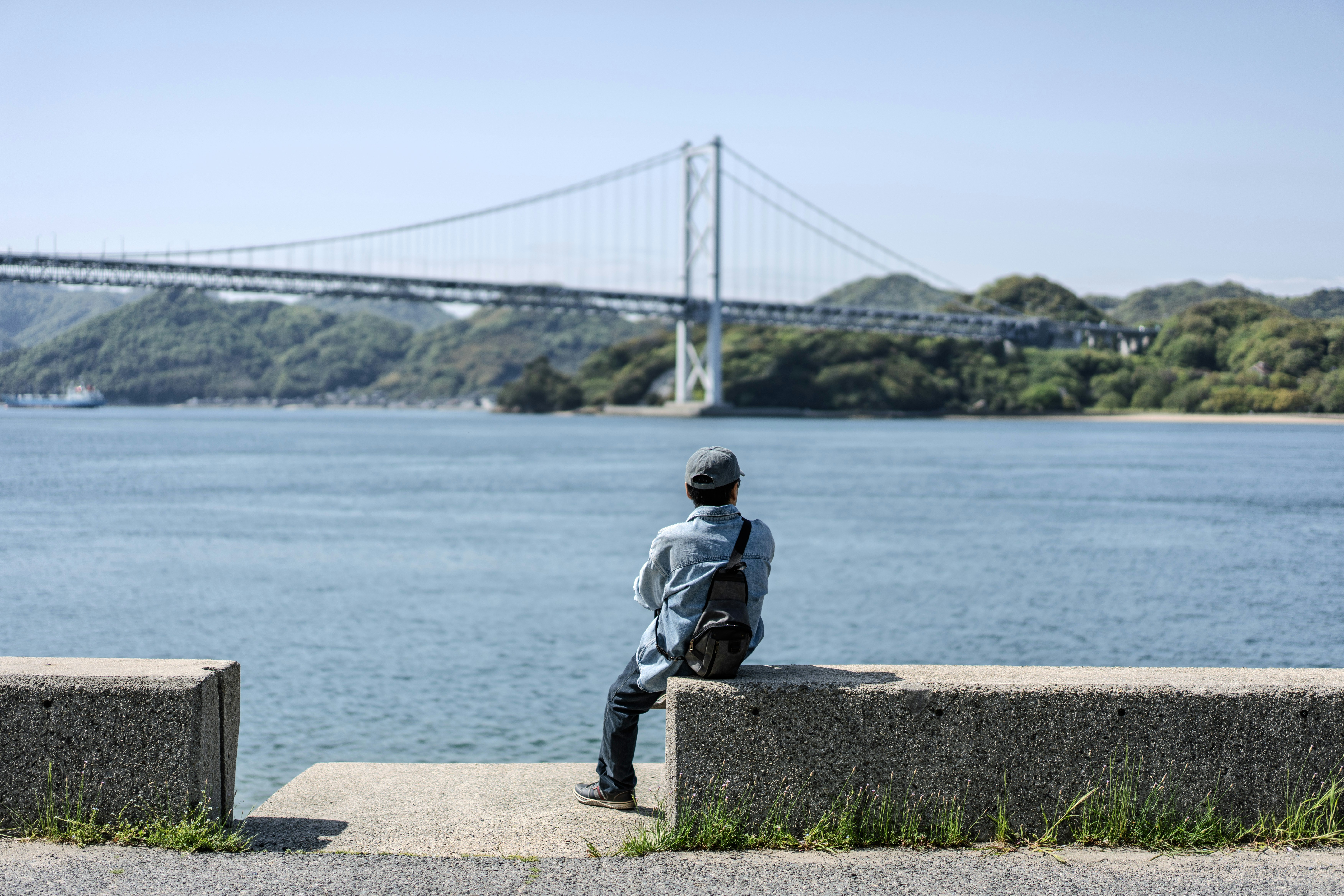 Una persona se sienta y mira hacia el agua.
