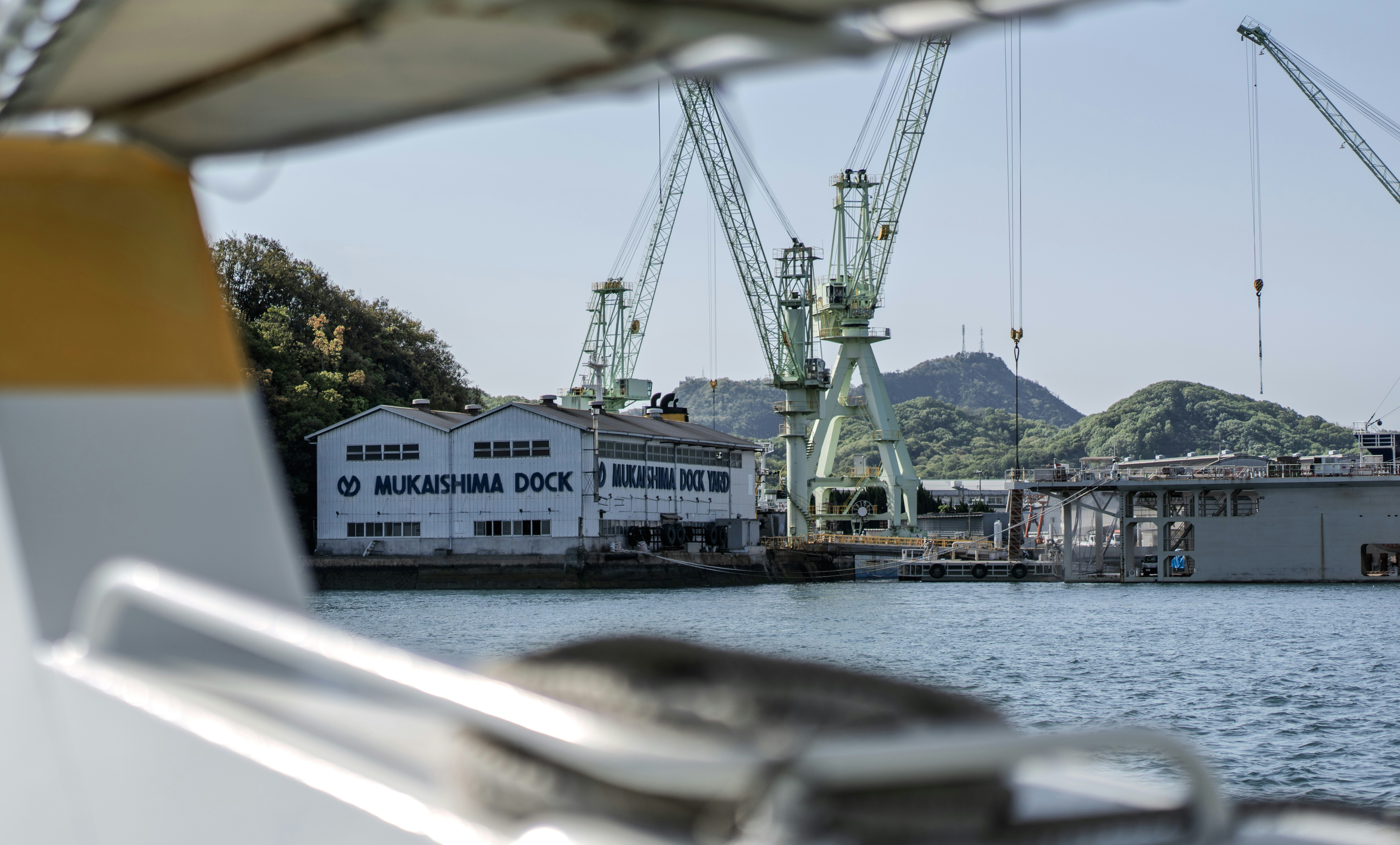 La imagen muestra un astillero con grúas y un edificio.