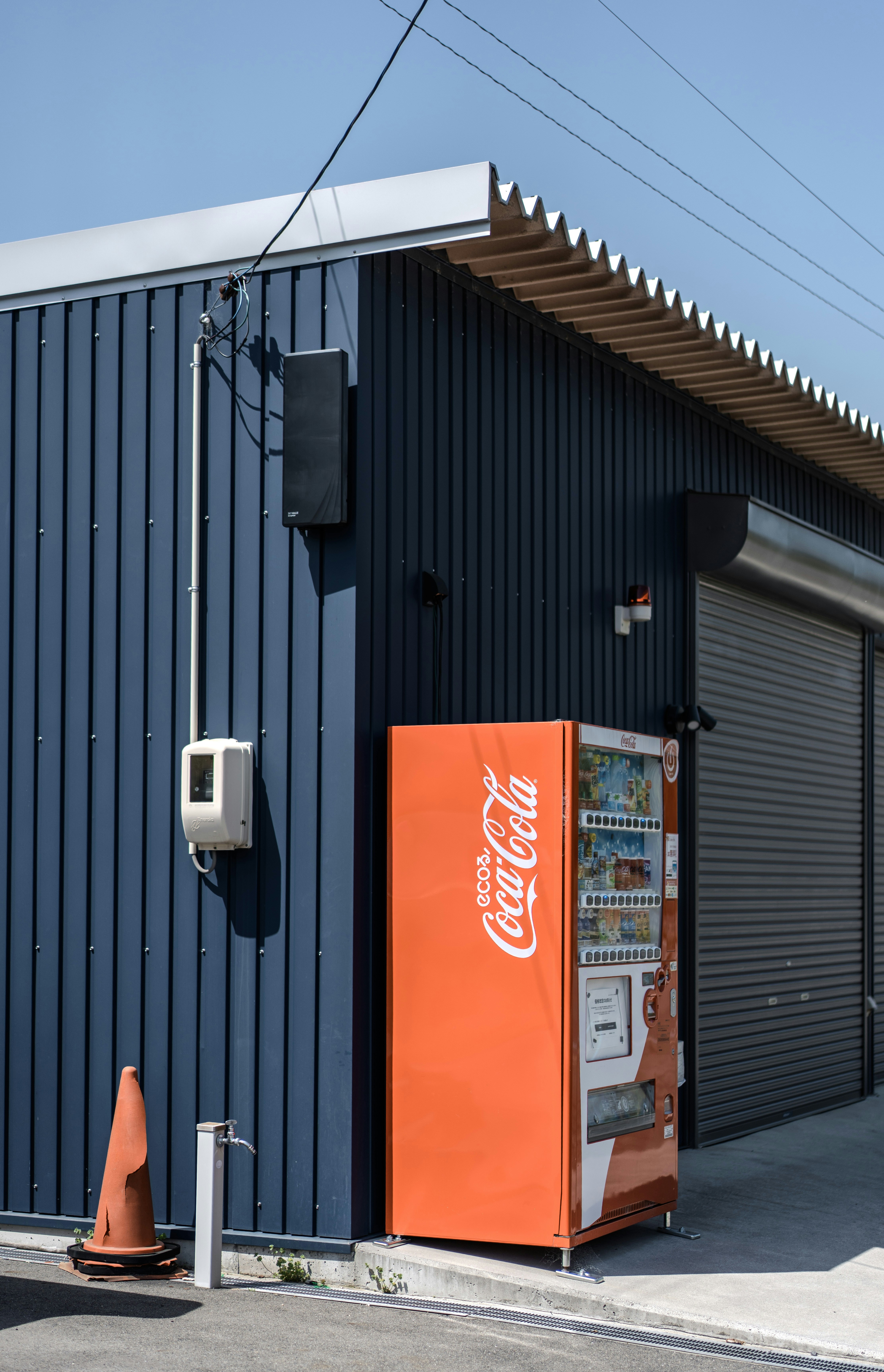 Una máquina expendedora de coca-cola se encuentra afuera de un edificio.