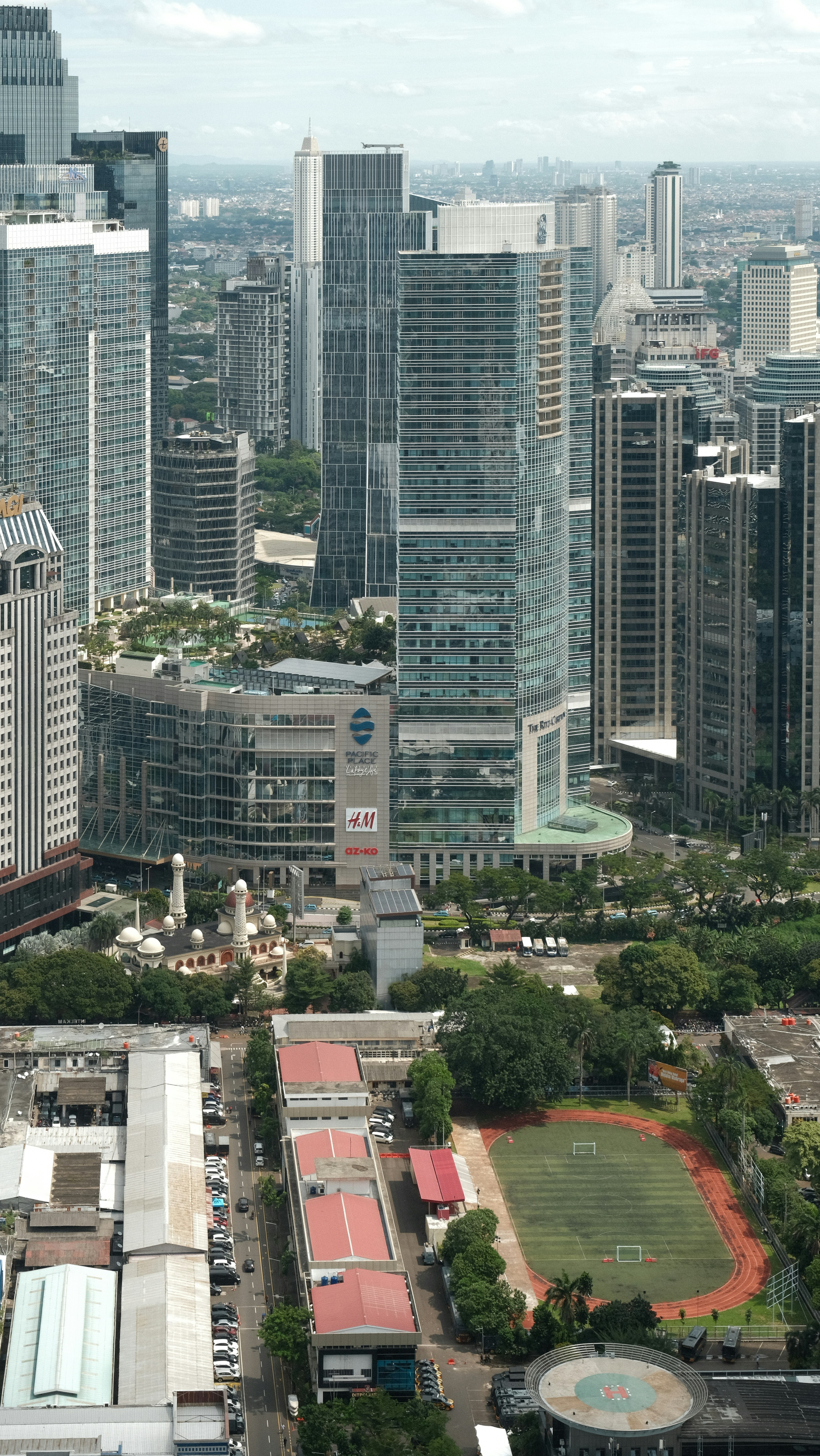 Cakrawala kota dengan gedung pencakar langit dan ruang hijau.