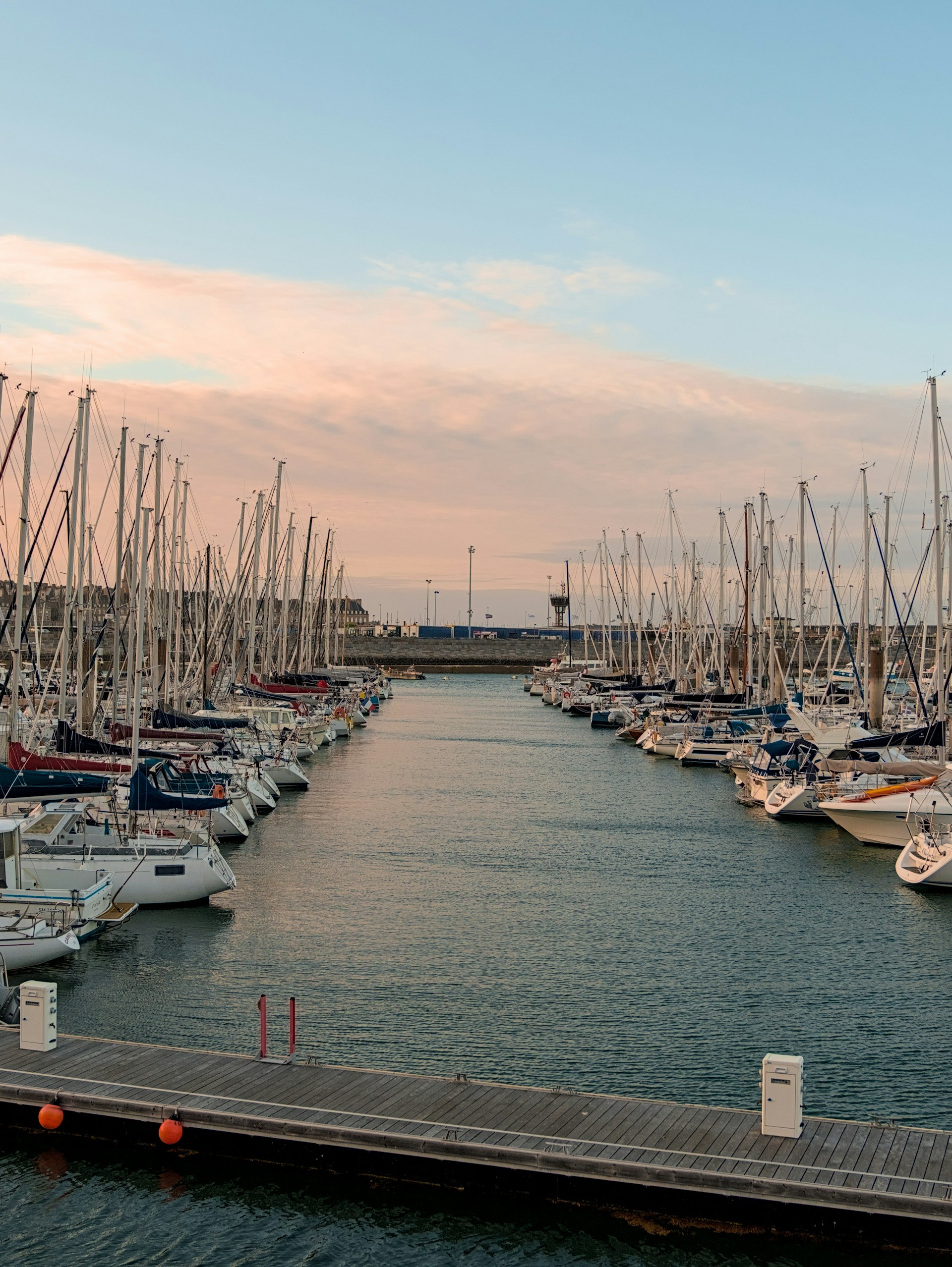Many sailboats are docked in a harbor.