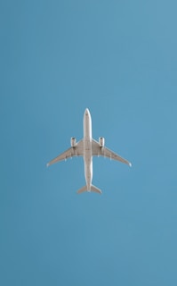 An airplane soars in the blue sky.