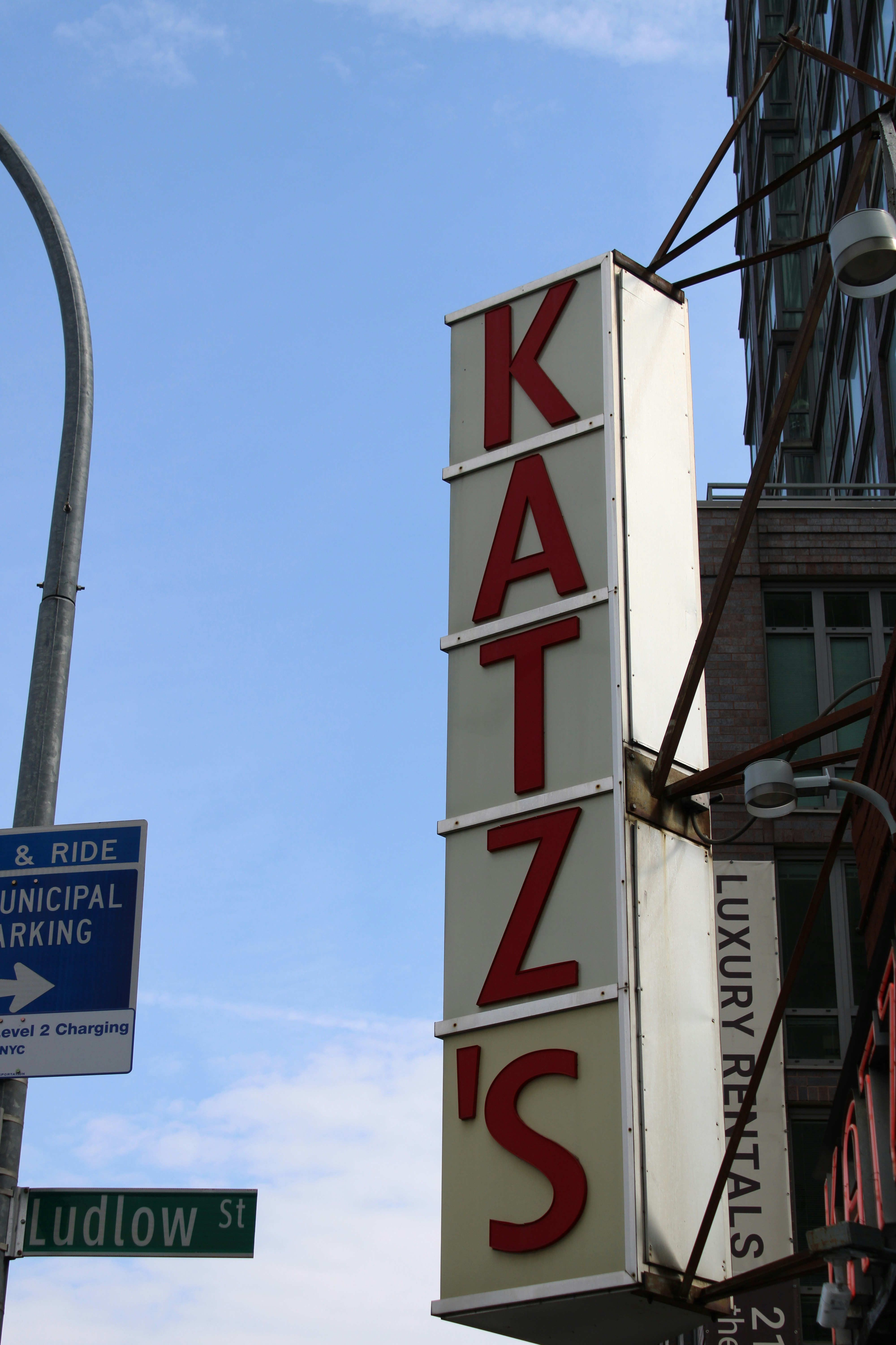 The katz's deli sign stands tall against the sky.
