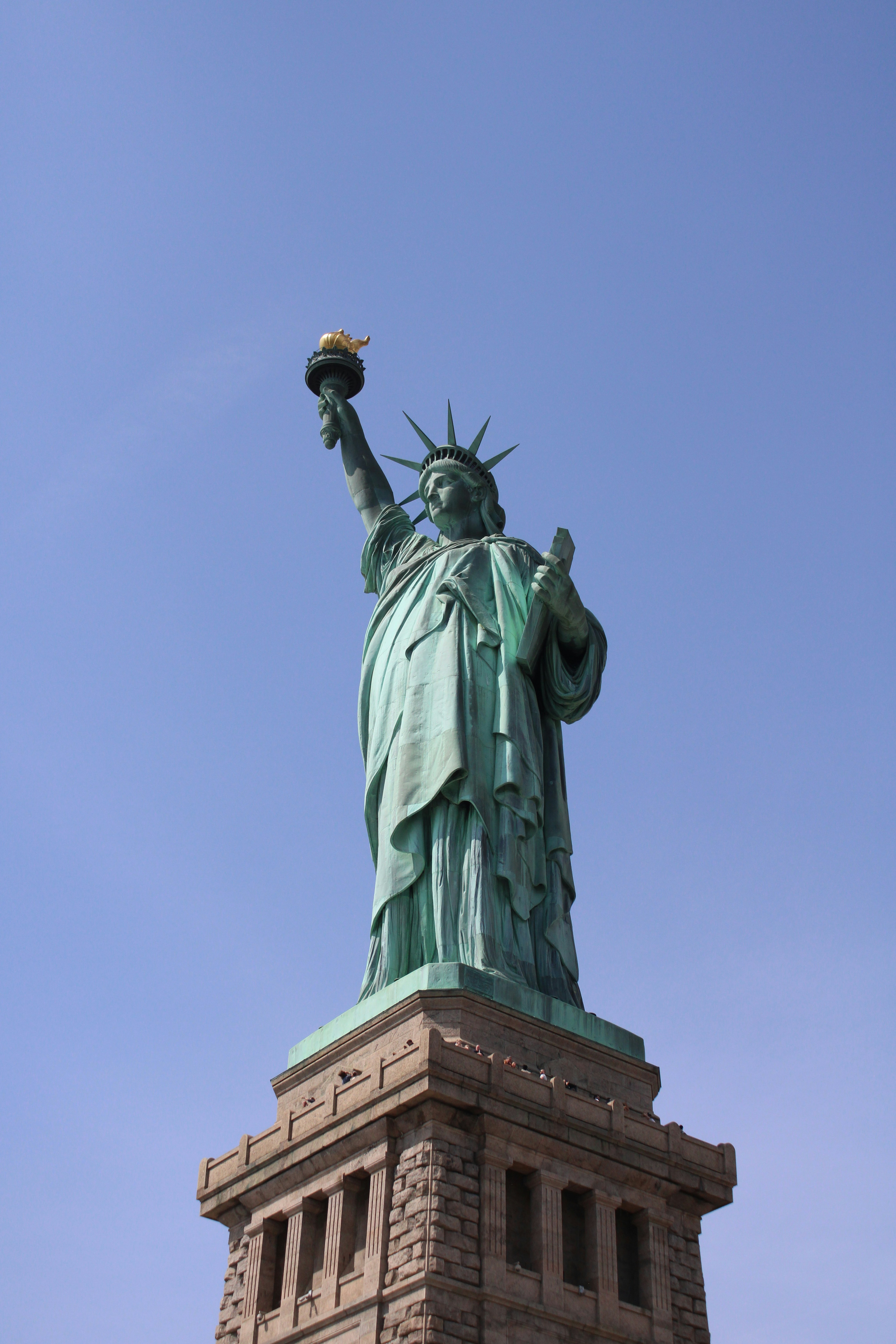 The statue of liberty stands tall against the blue sky.