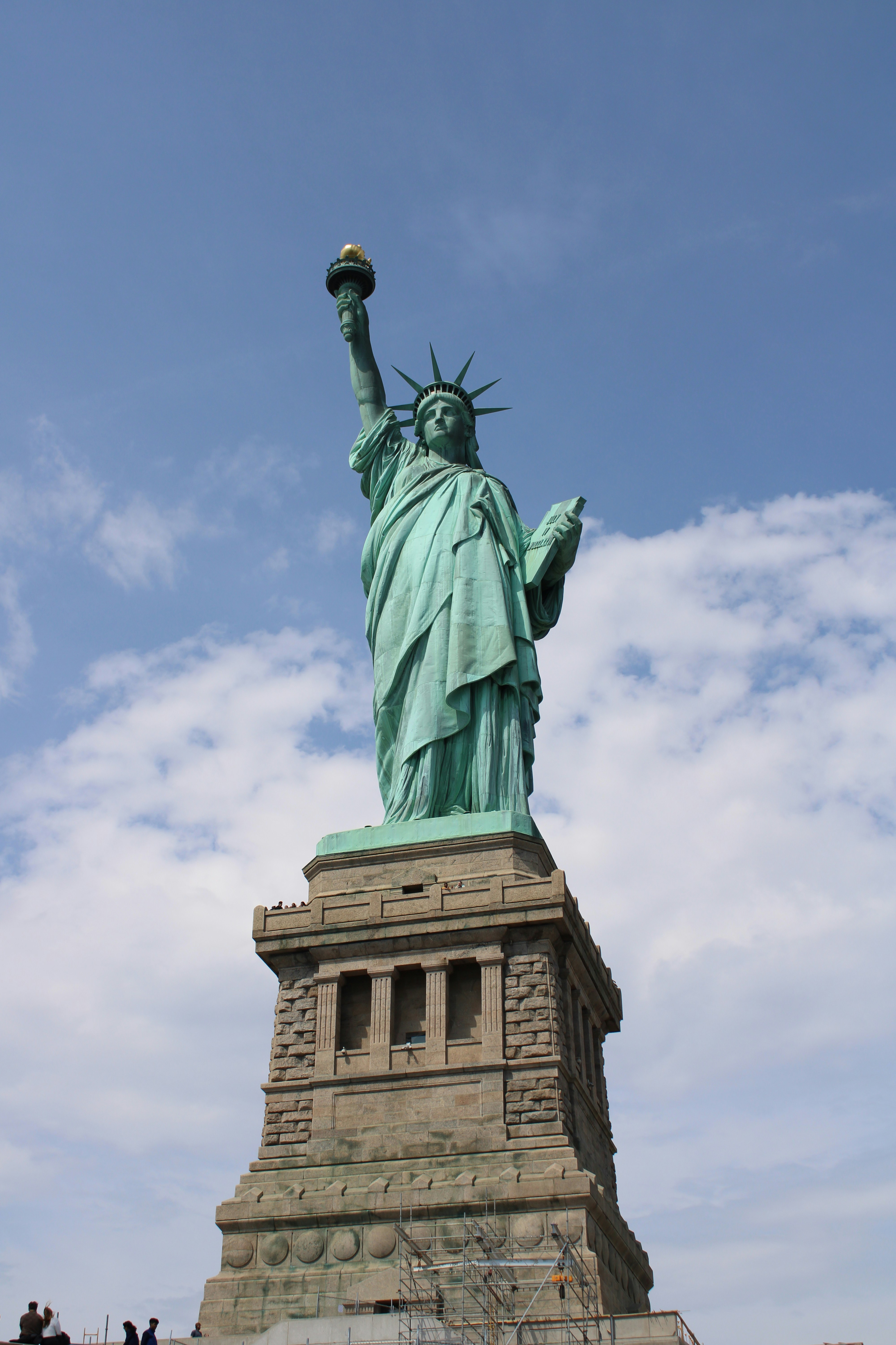 The statue of liberty stands tall against a blue sky.