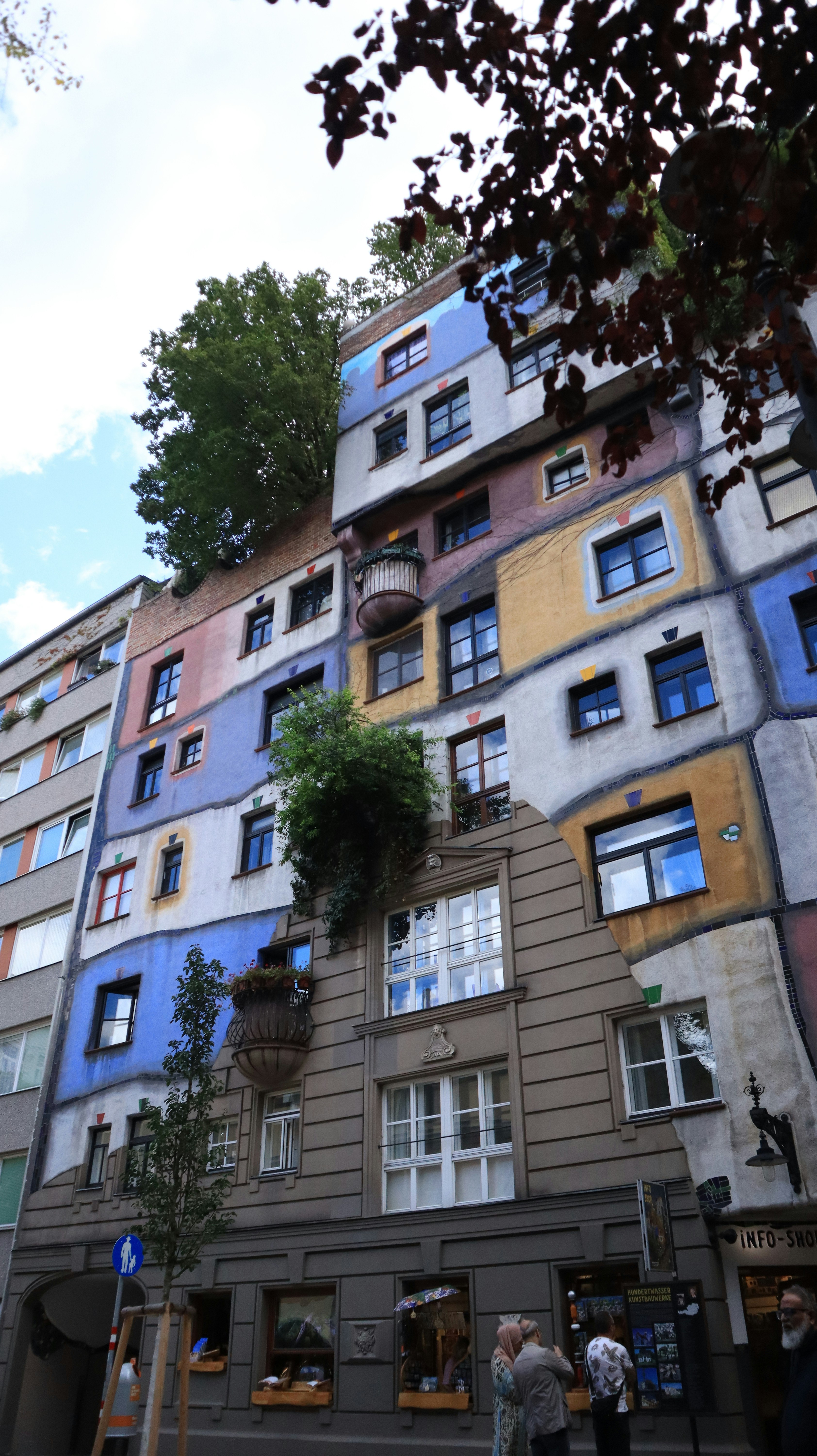 A colorful, unique building with trees growing on it.