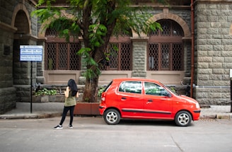A red car is parked near a building.
