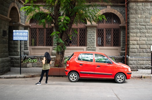 A red car is parked near a building.
