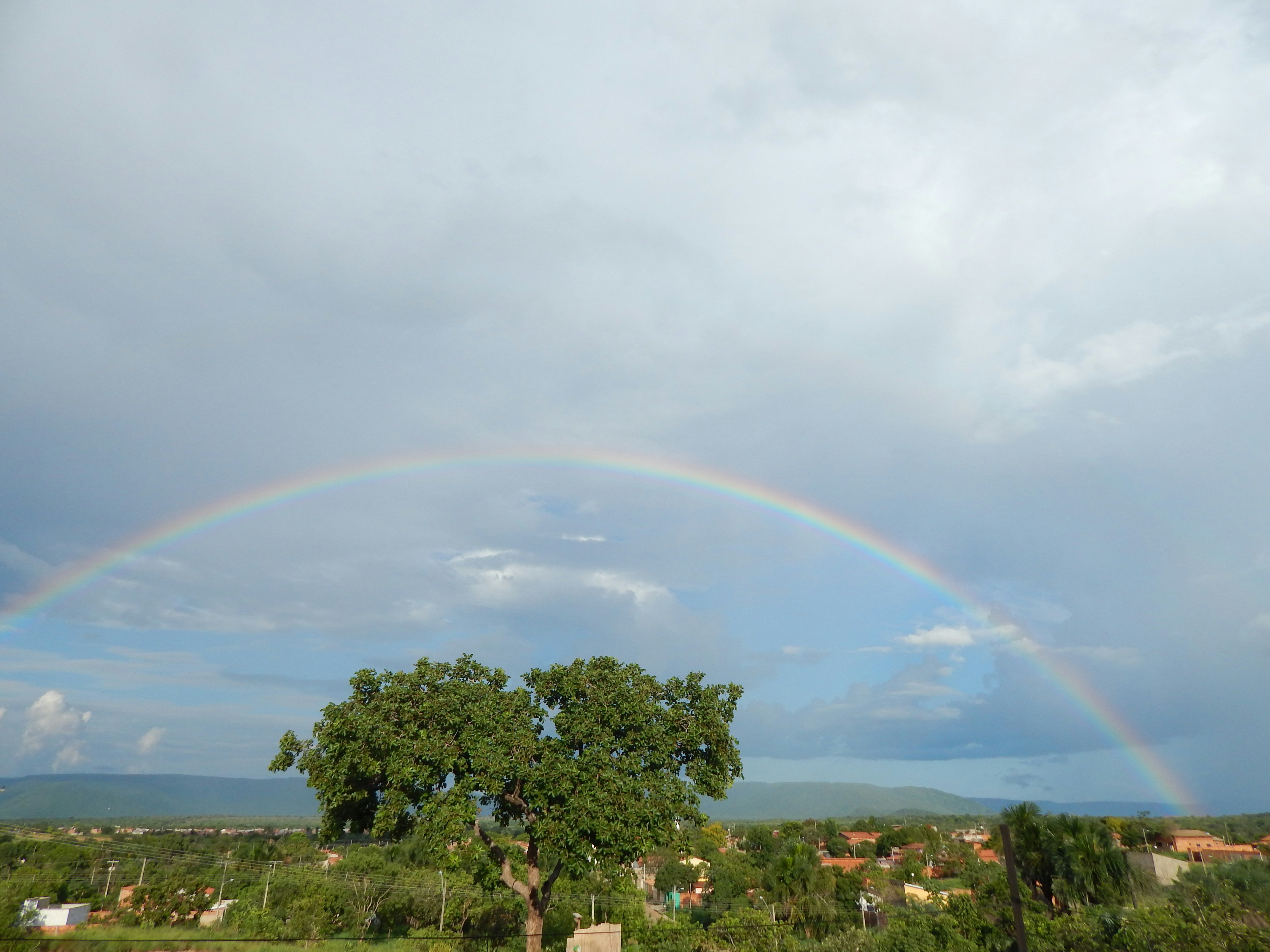A rainbow arches over a green landscape.