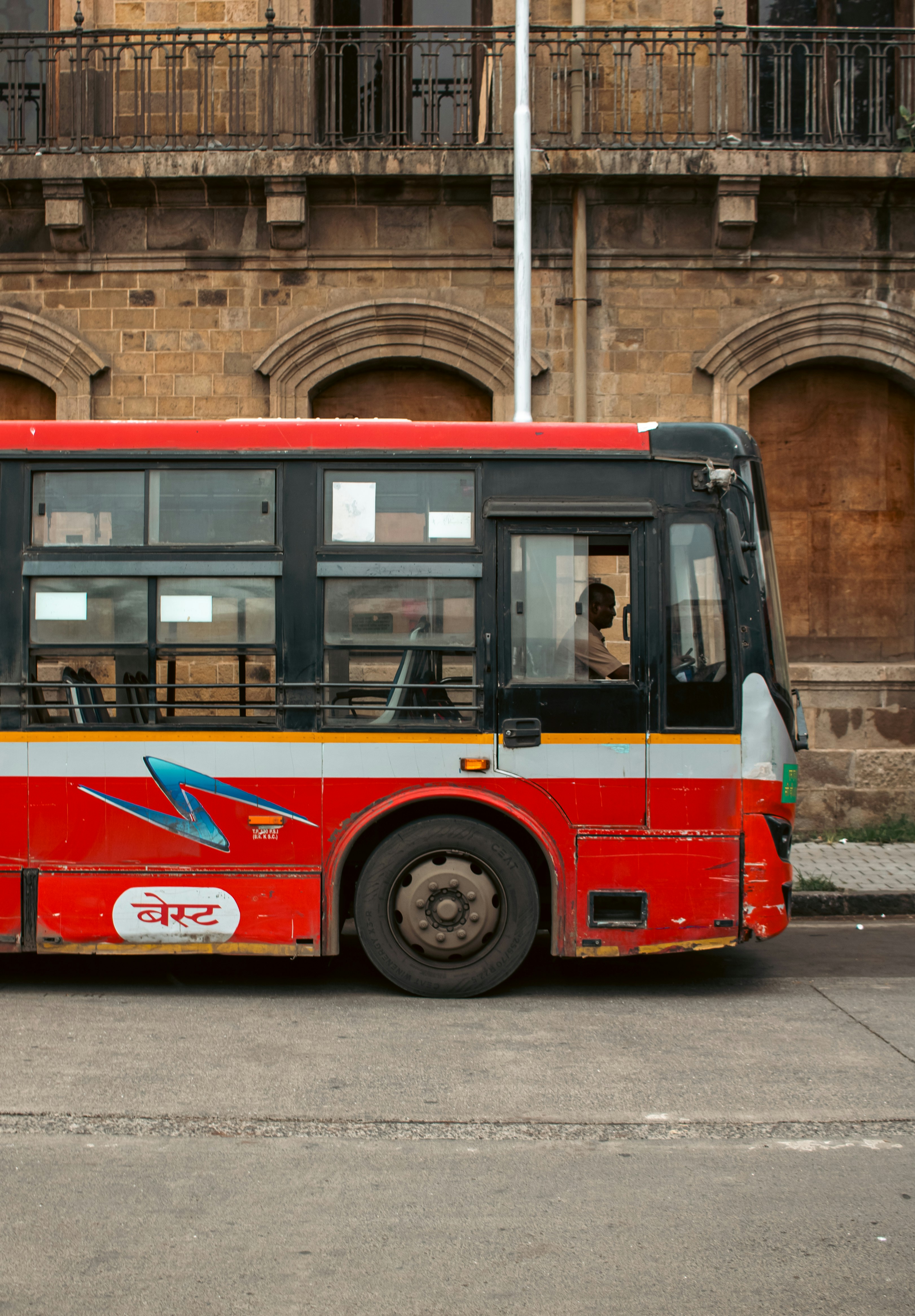 A red bus is parked in front of an old building.